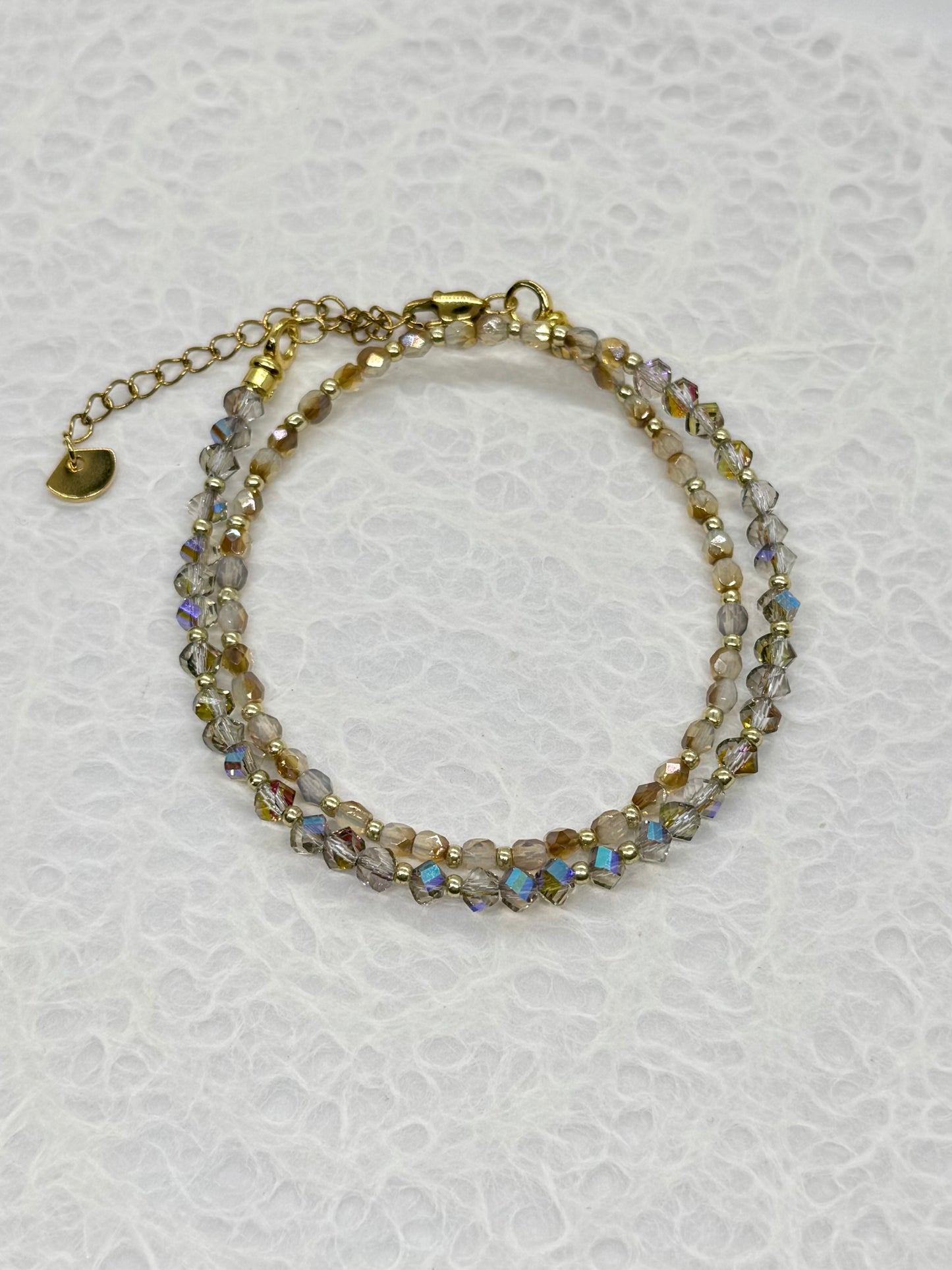 Multistrand beaded bracelet with gold accents on a textured white background