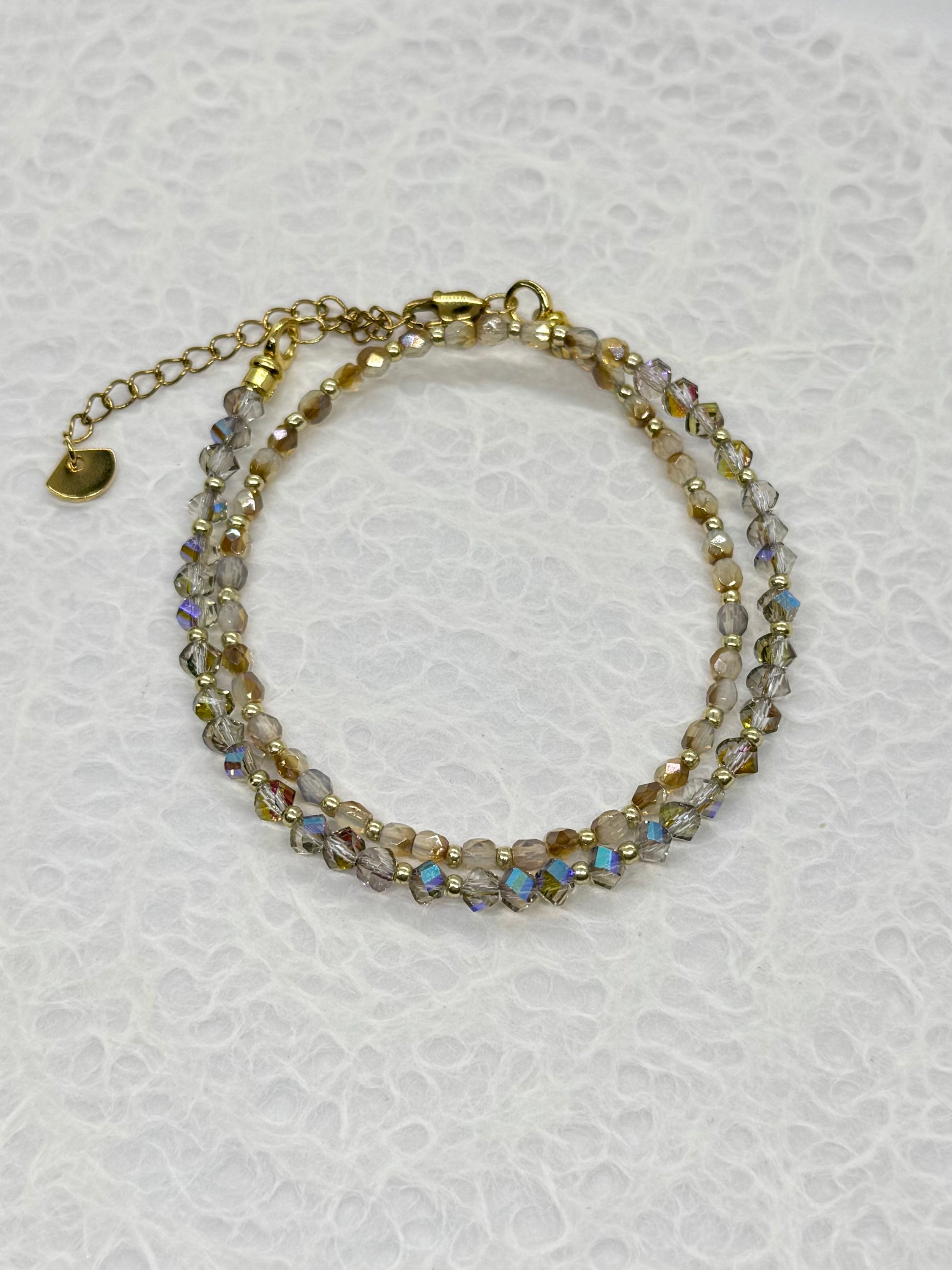 Multistrand beaded bracelet with gold accents on a textured white background