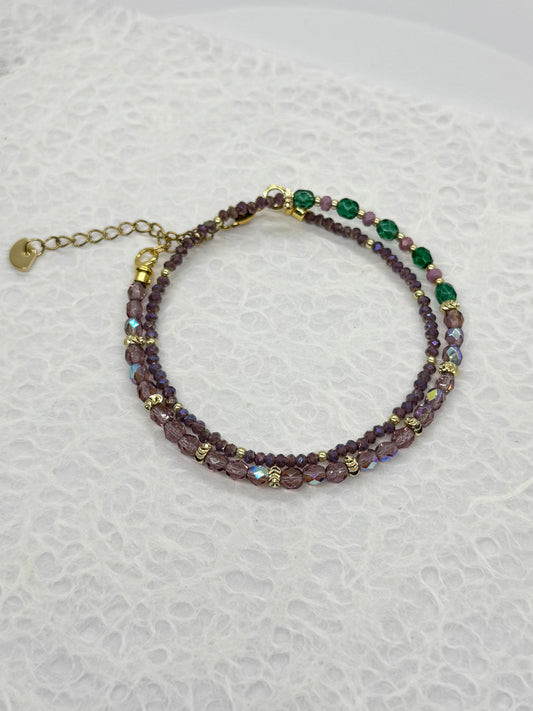 Beaded bracelet with purple and green beads on a textured white background