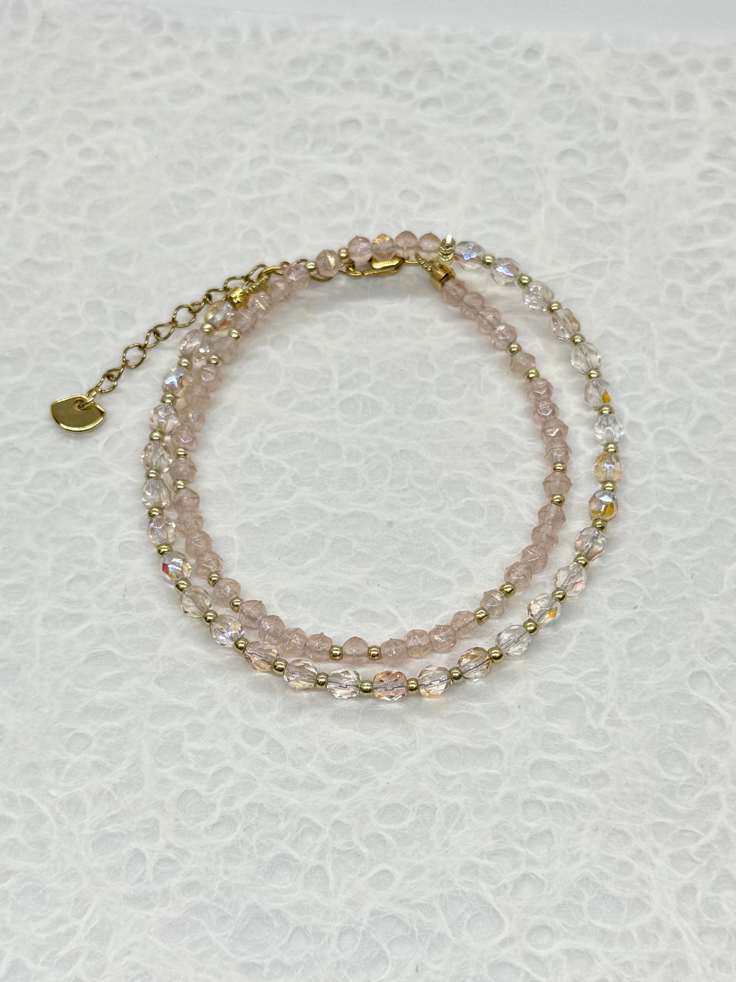 Two layered beaded bracelets on a textured white surface