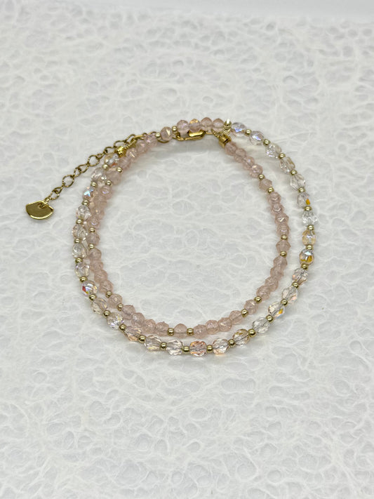 Two layered beaded bracelets on a textured white surface