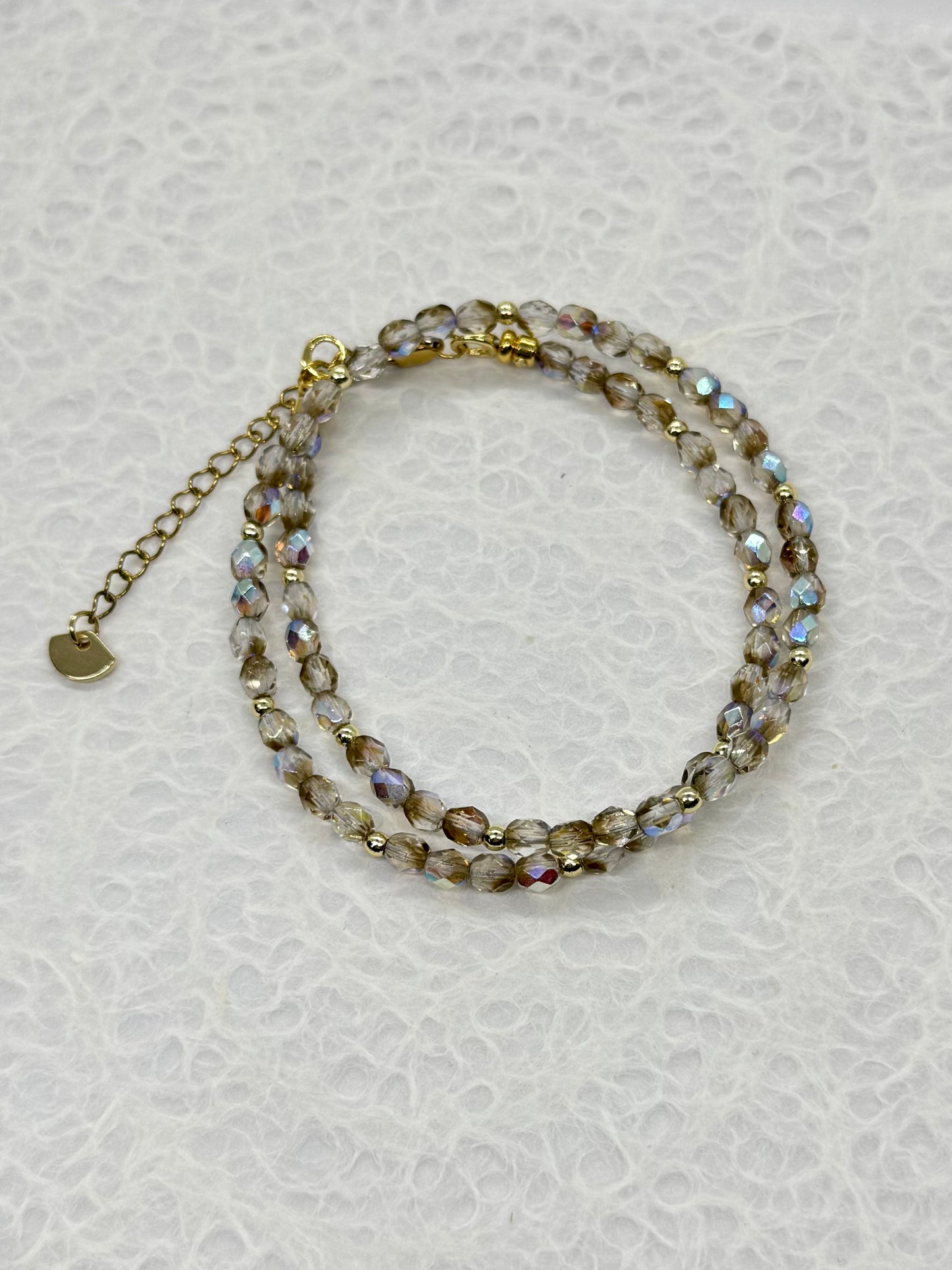 Beaded bracelet with gold chain on a light gray background