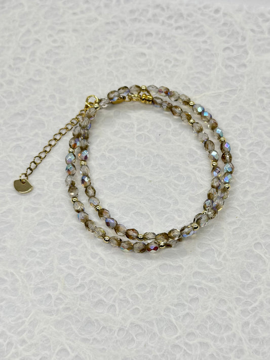 Beaded bracelet with gold chain on a light gray background