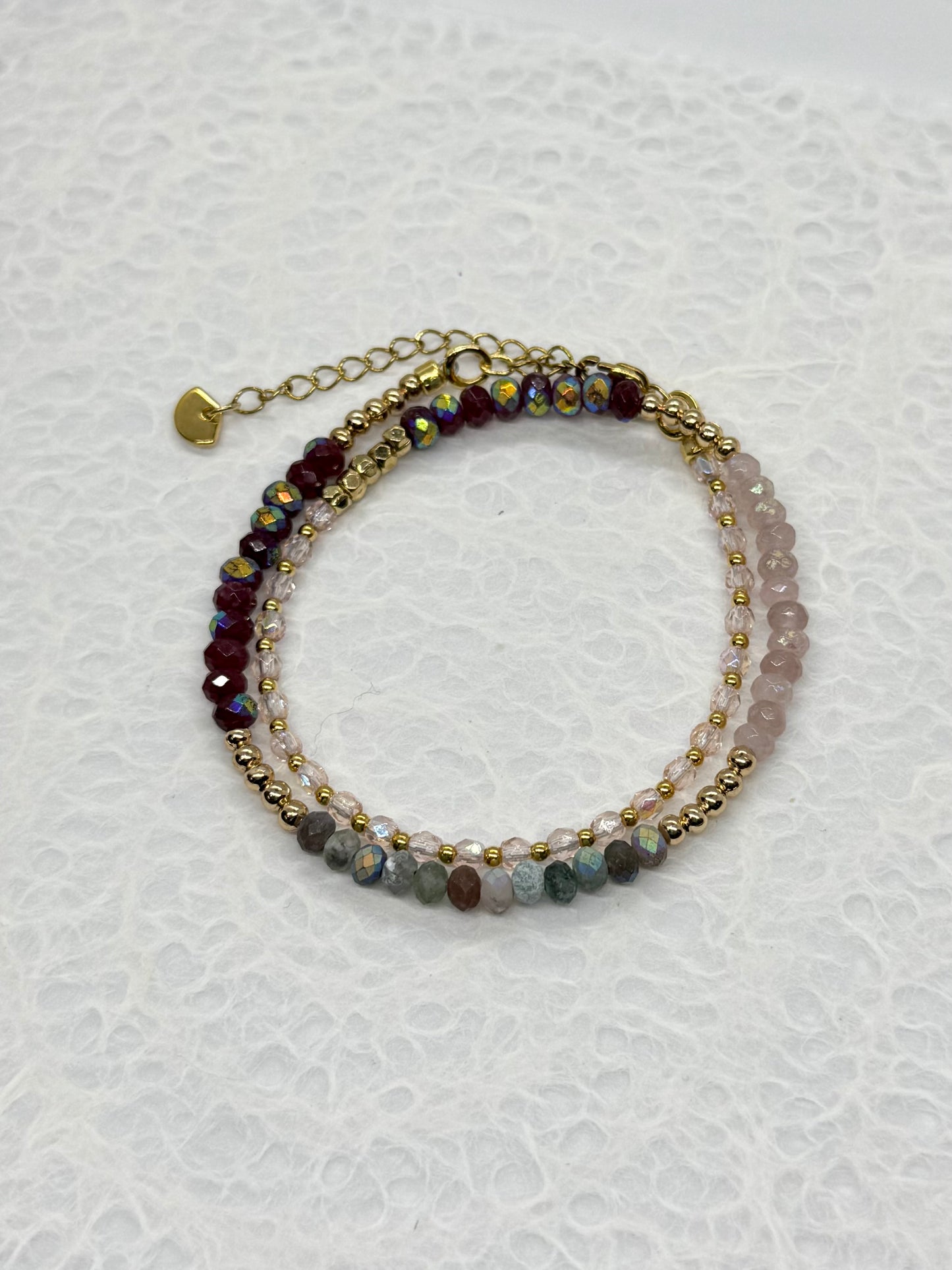 Stack of beaded bracelets on a textured white background