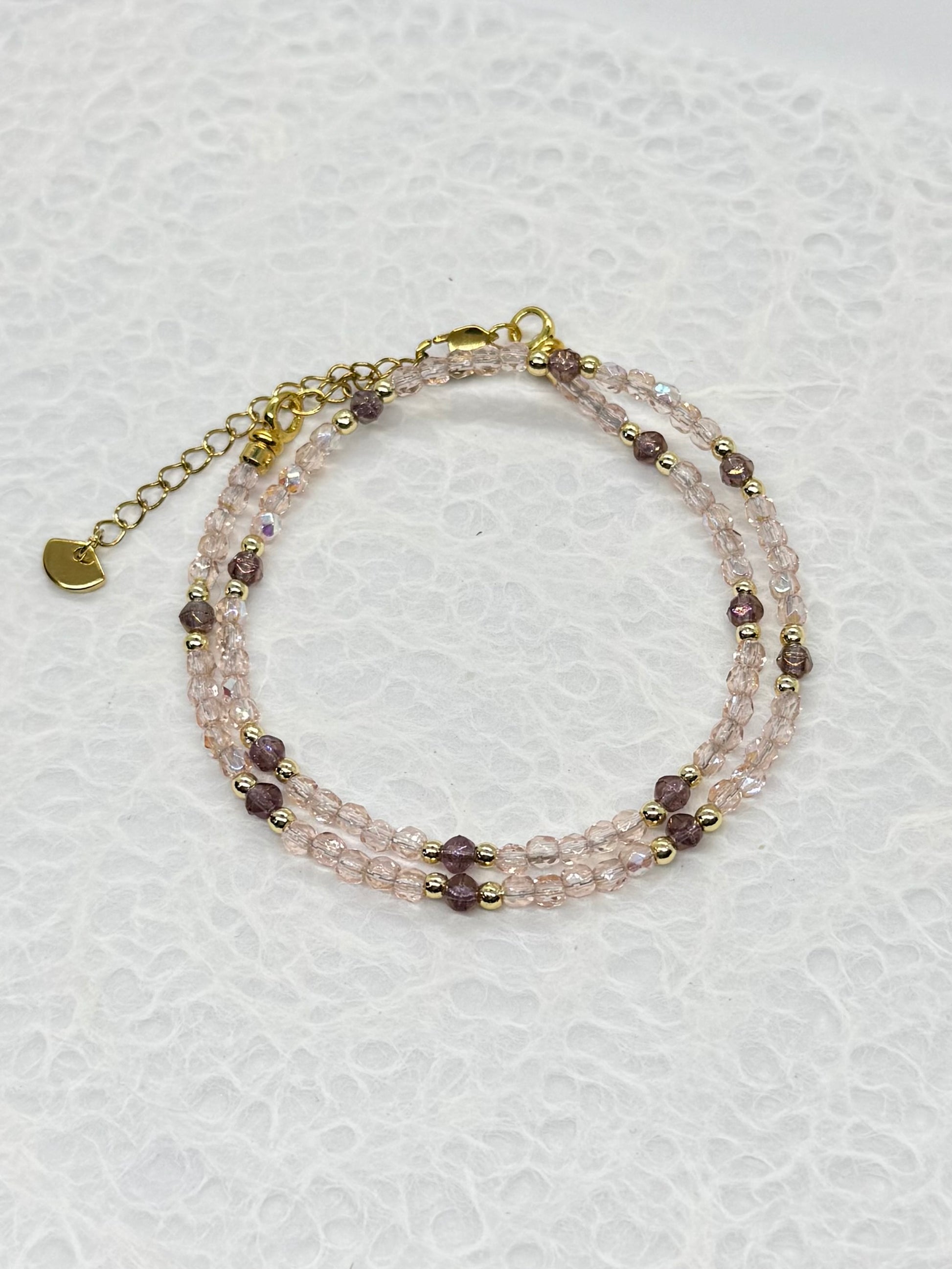 Multistrand beaded bracelet with gold chain on a light gray background
