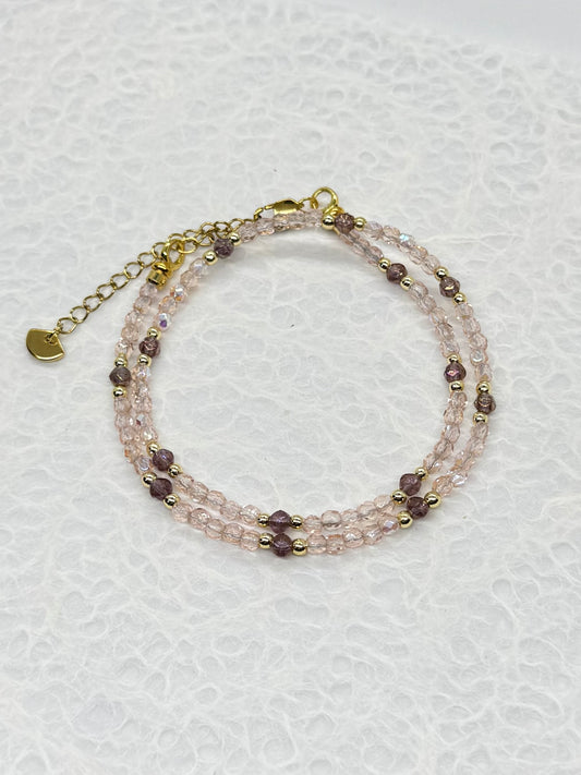 Multistrand beaded bracelet with gold chain on a light gray background