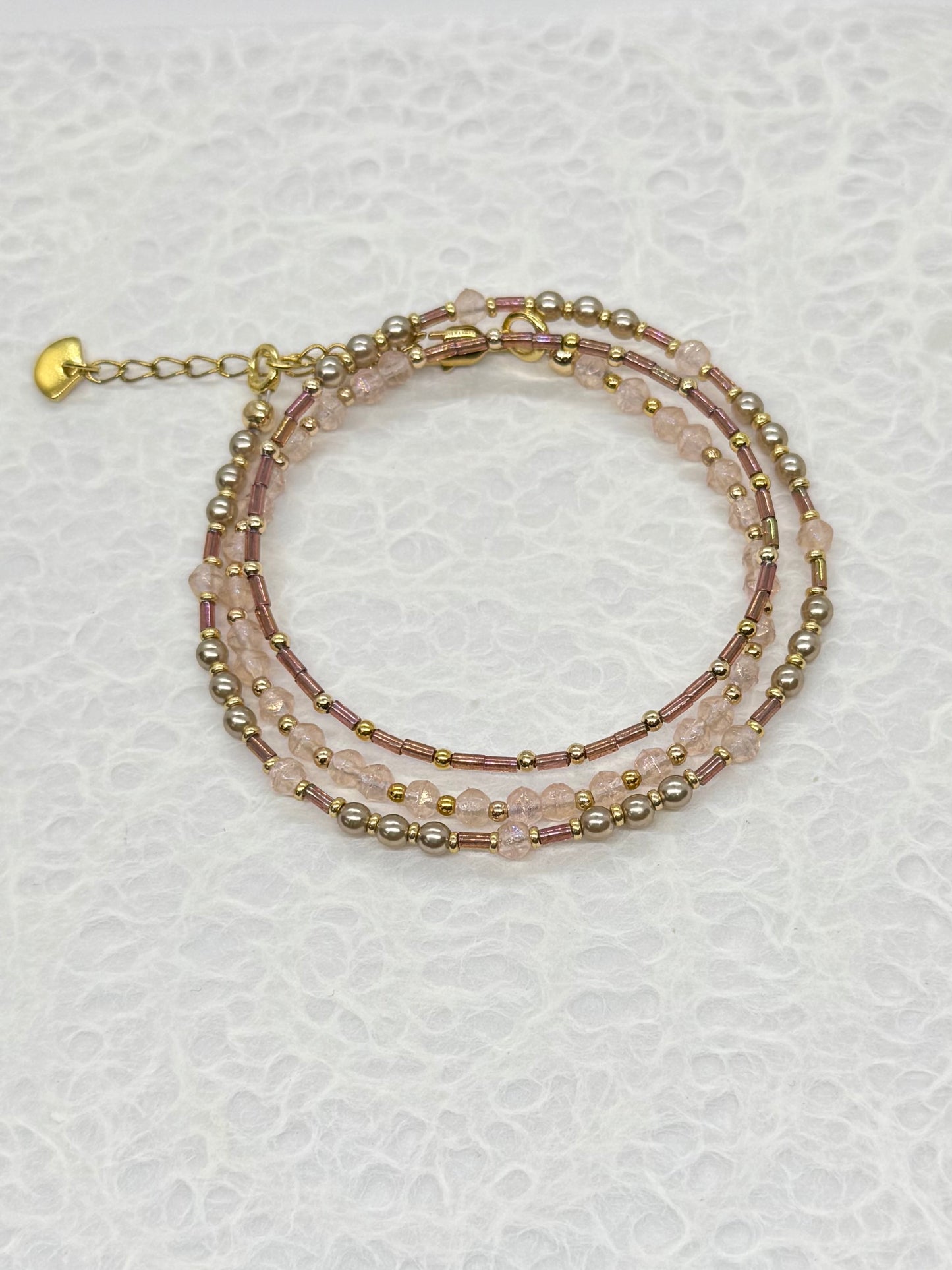 Multistrand beaded bracelet with gold accents on a textured white background