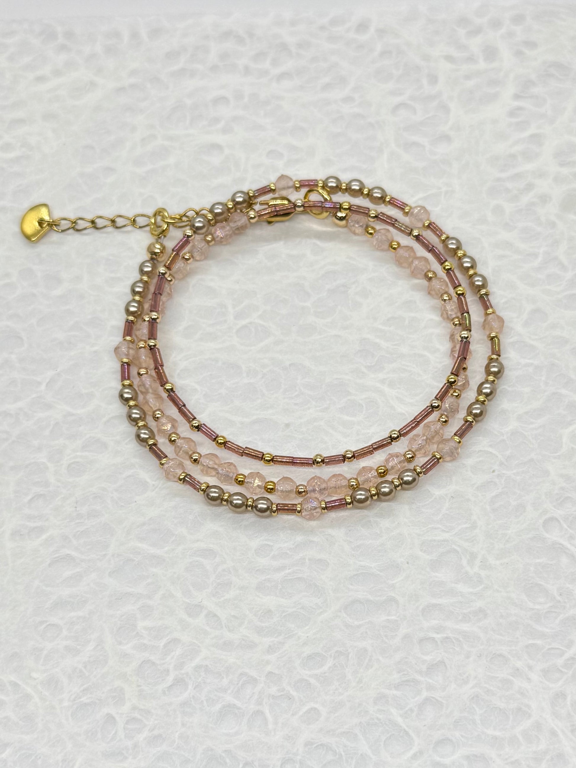 Multistrand beaded bracelet with gold accents on a textured white background