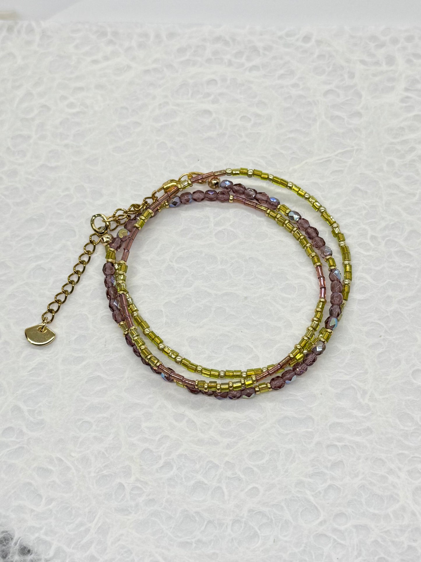 Stack of beaded bracelets on a textured white surface