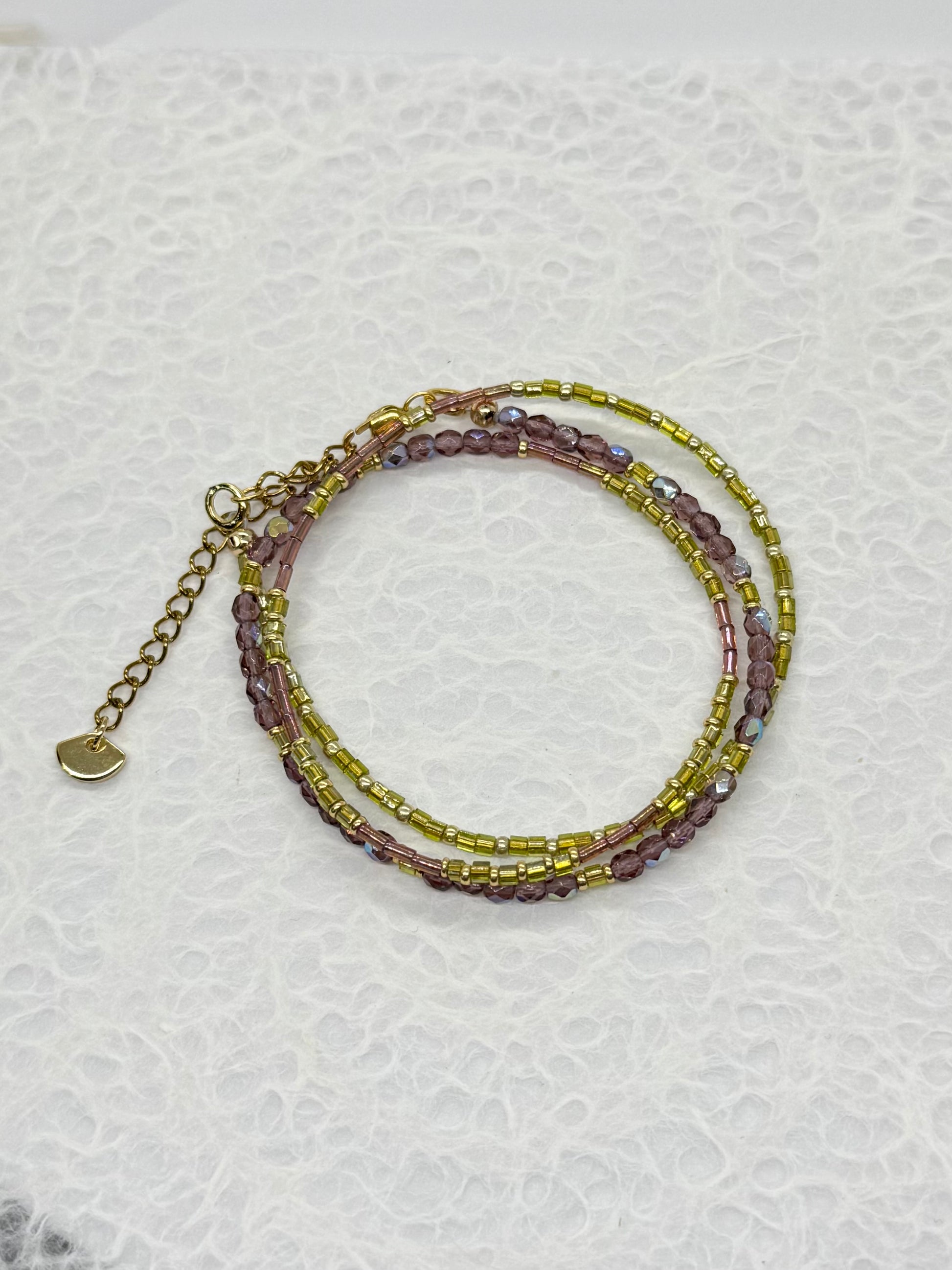 Stack of beaded bracelets on a textured white surface