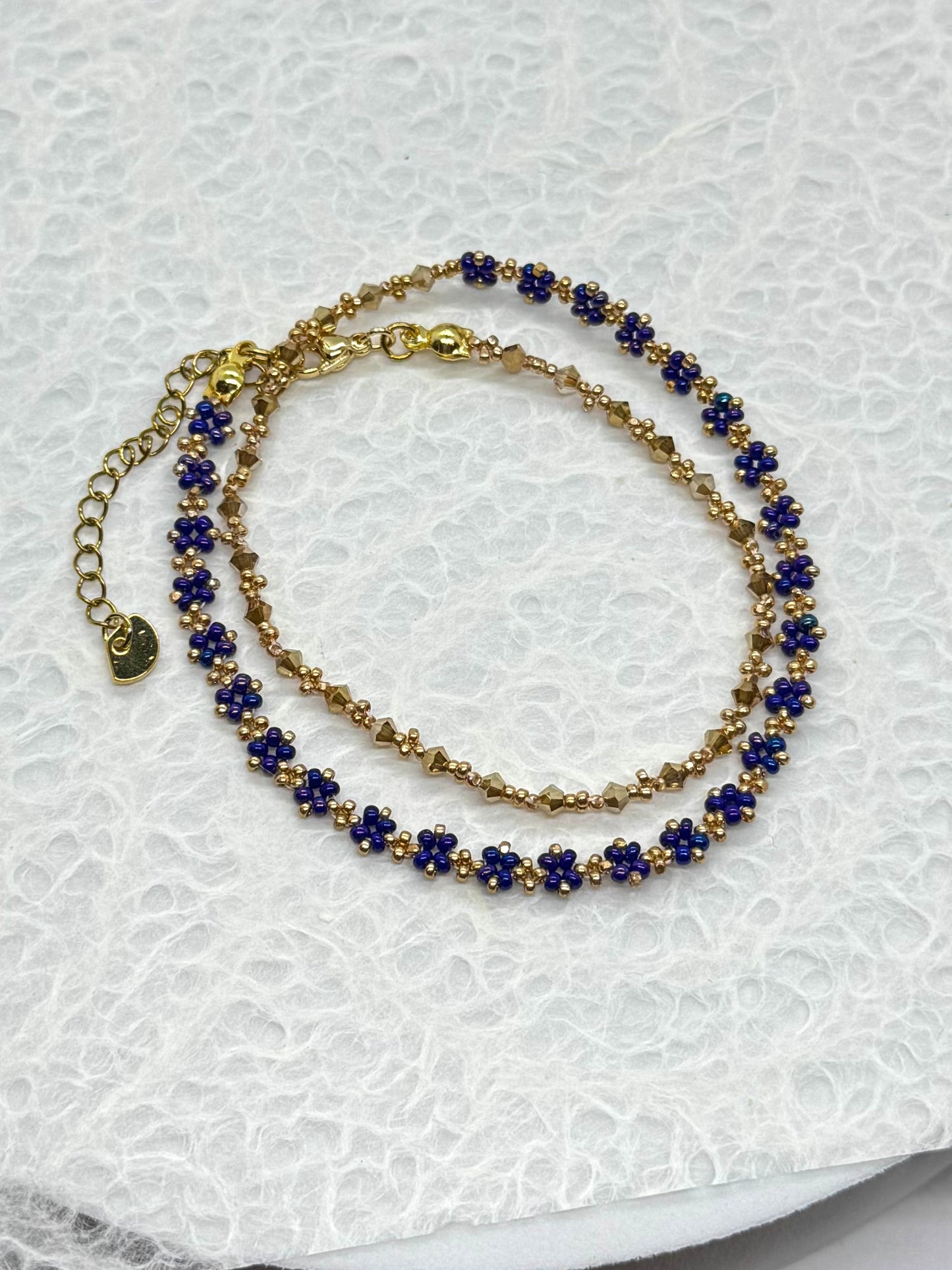 Gold and blue beaded bracelet on a textured white surface