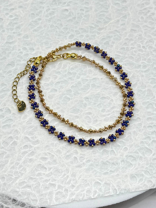 Gold and blue beaded bracelet on a textured white surface