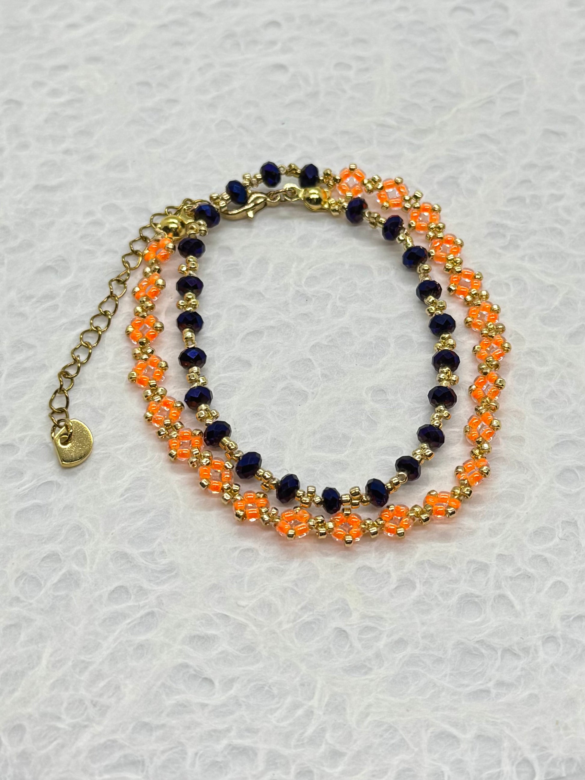 Two layered bracelets with orange and navy beads on a light gray background