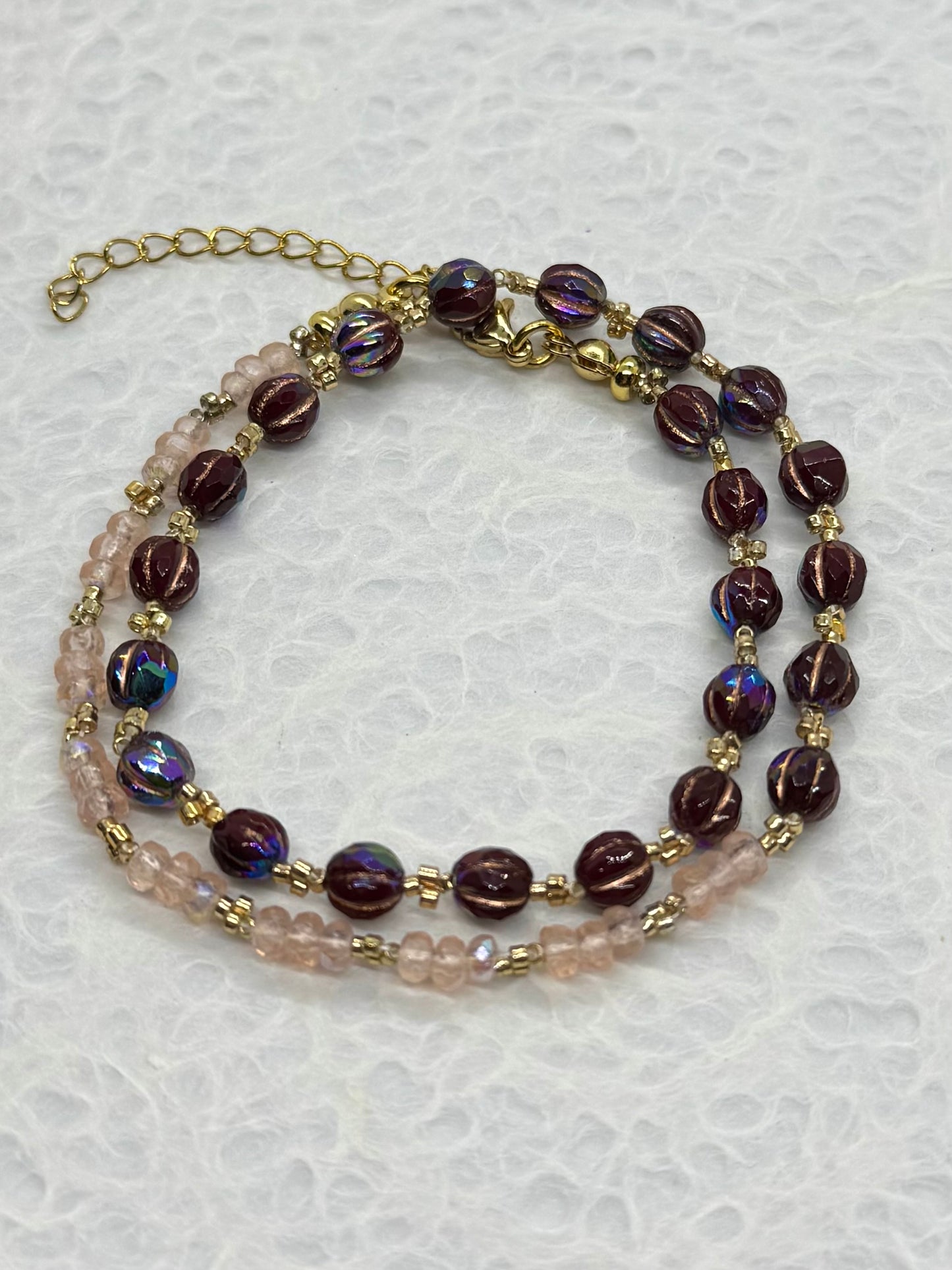 Beaded necklace with purple and gold beads on a light gray background