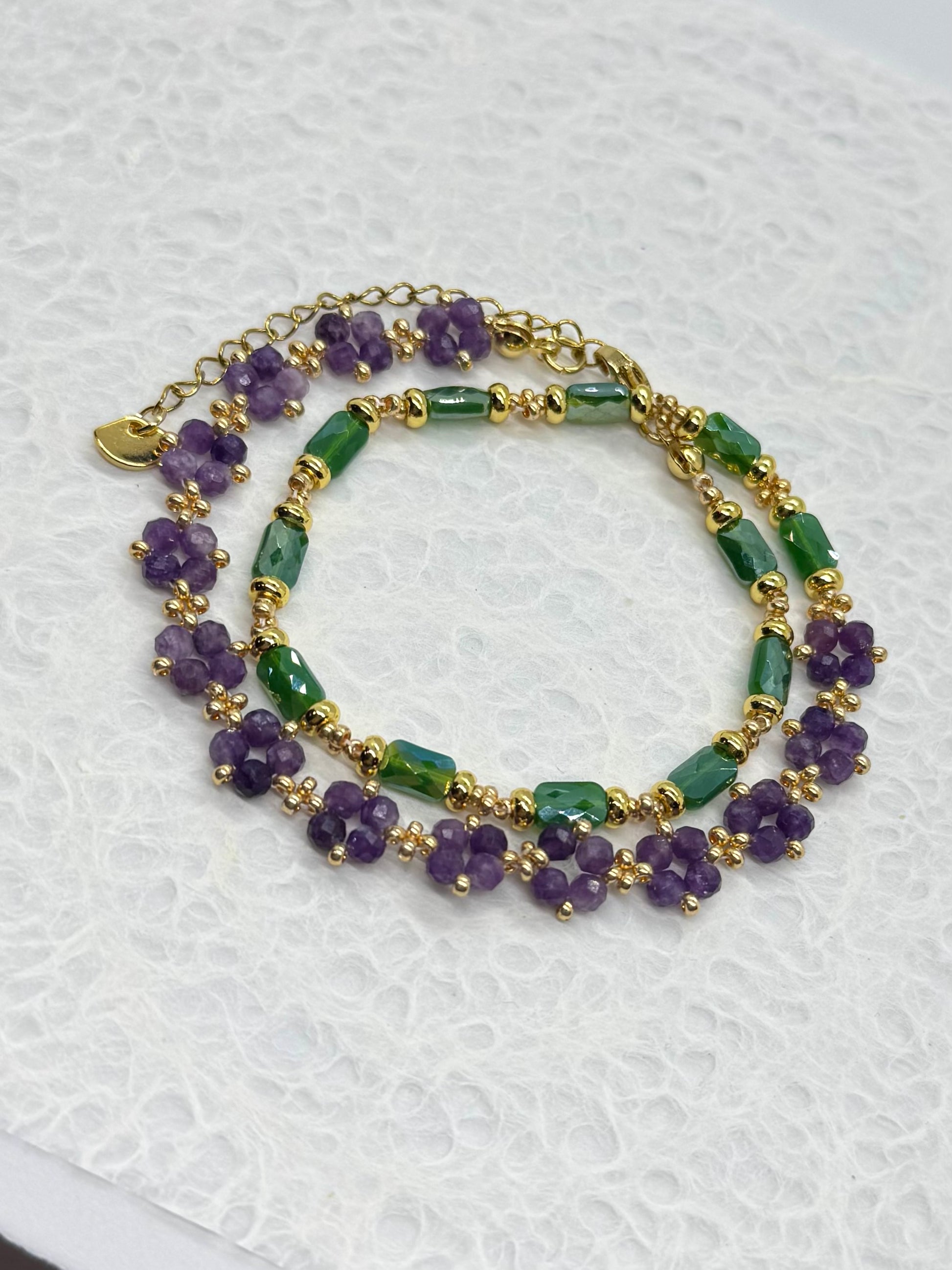 Two beaded bracelets with purple and green beads on a white background