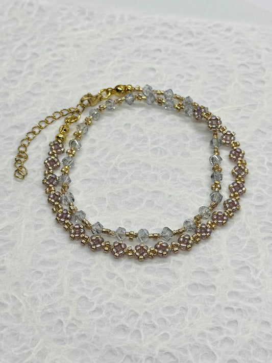 Two-layered beaded bracelet with gold chain on a textured white background