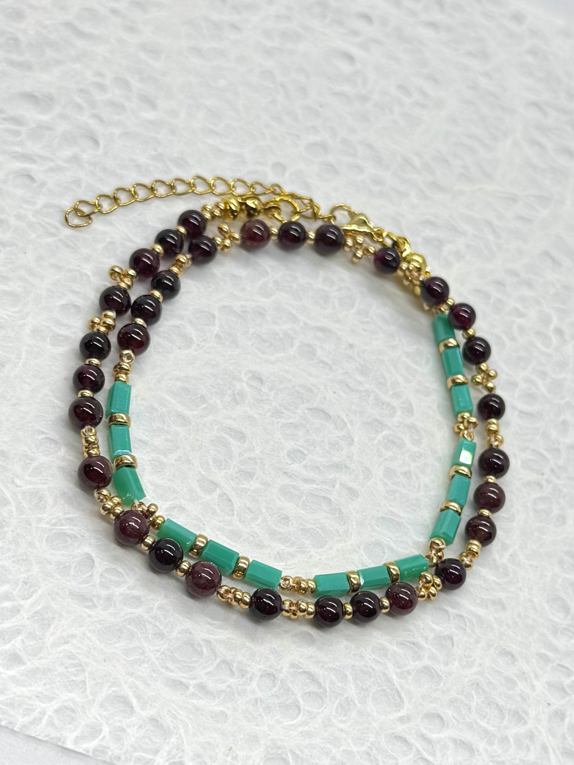 Multistrand beaded necklace with gold chain on a textured white background
