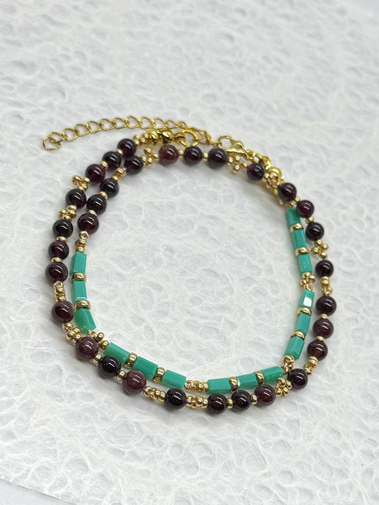 Multistrand beaded necklace with gold chain on a textured white background