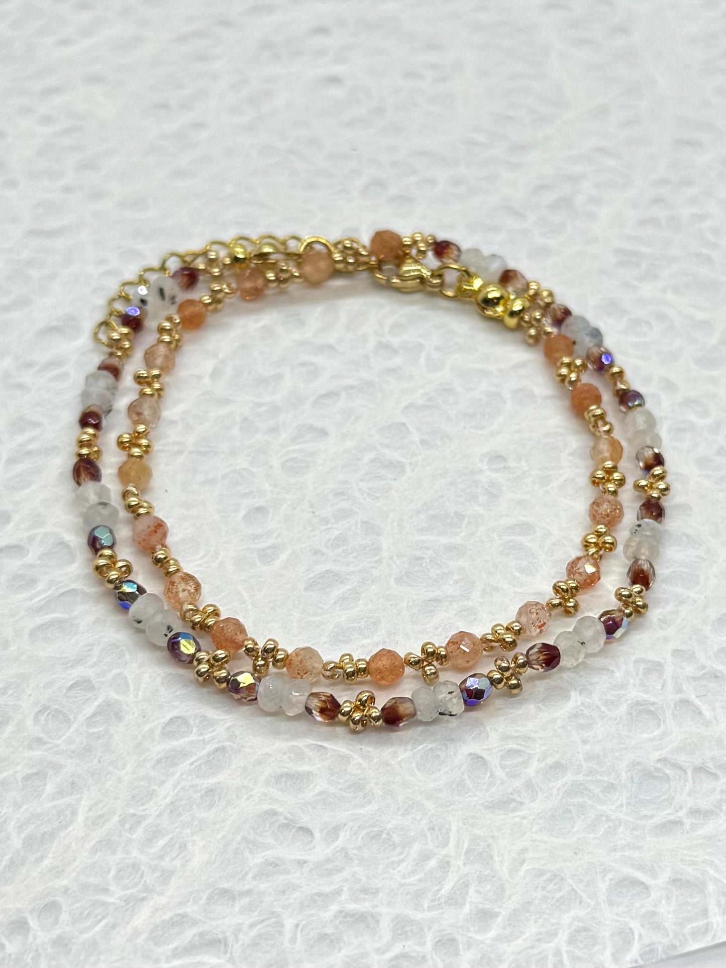 Multicolored beaded bracelet with gold accents on a white background
