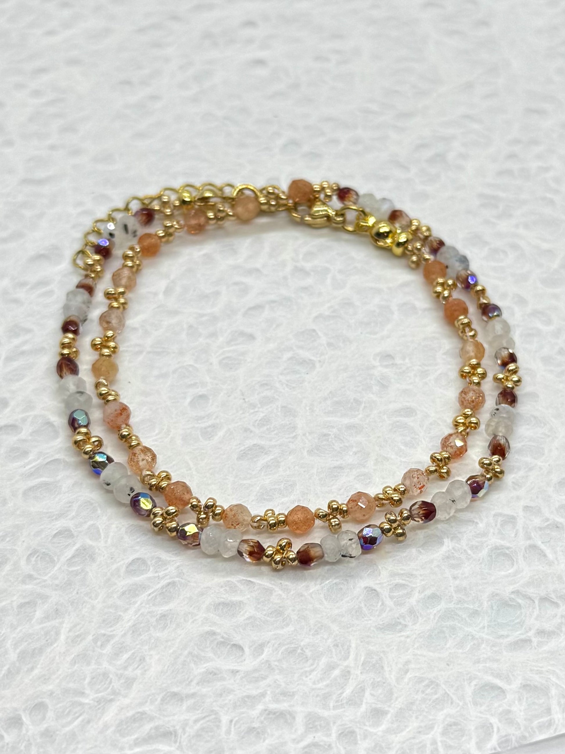 Multicolored beaded bracelet with gold accents on a white background