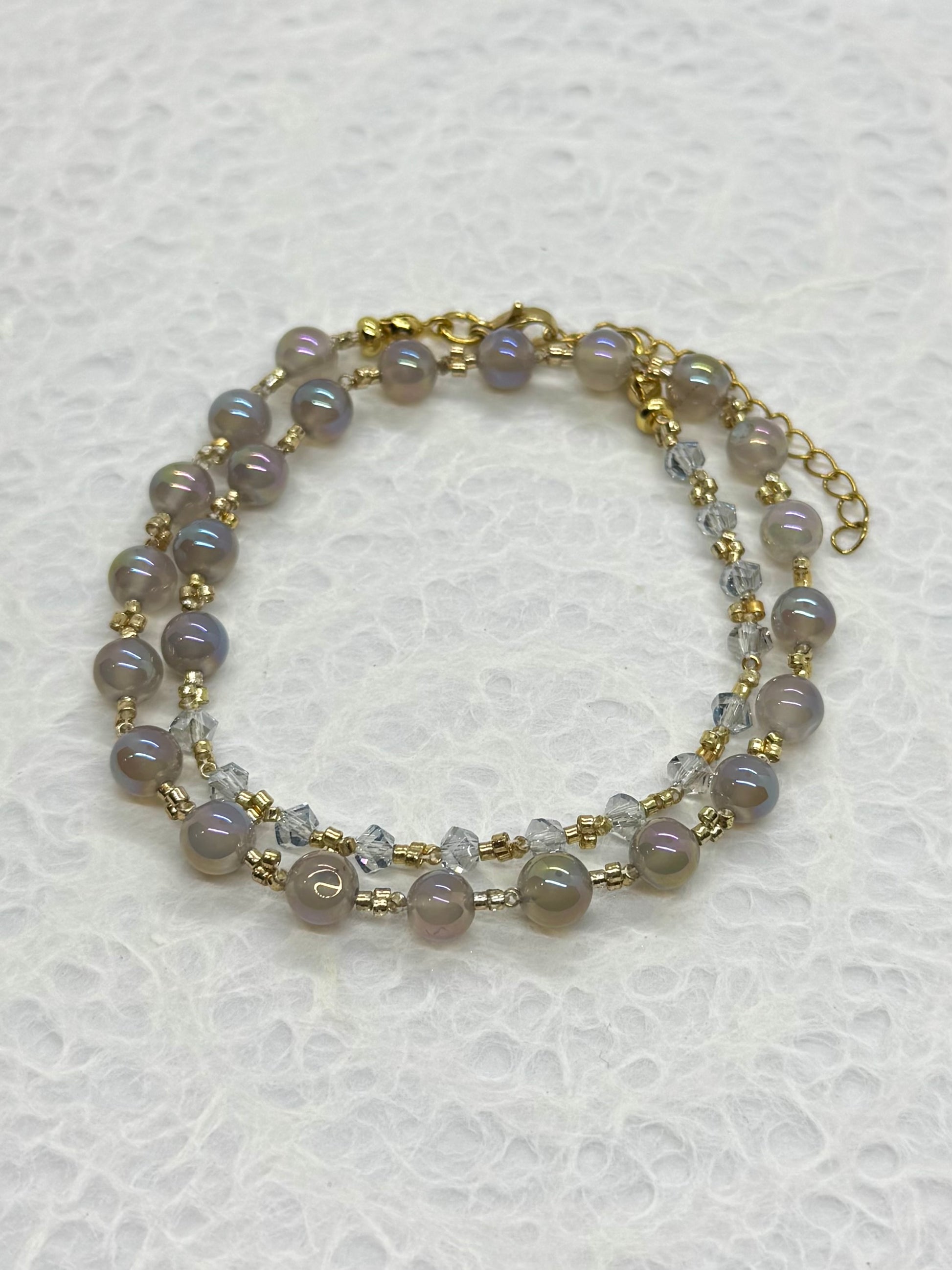 Two-layered beaded bracelet with gold accents on a textured white background