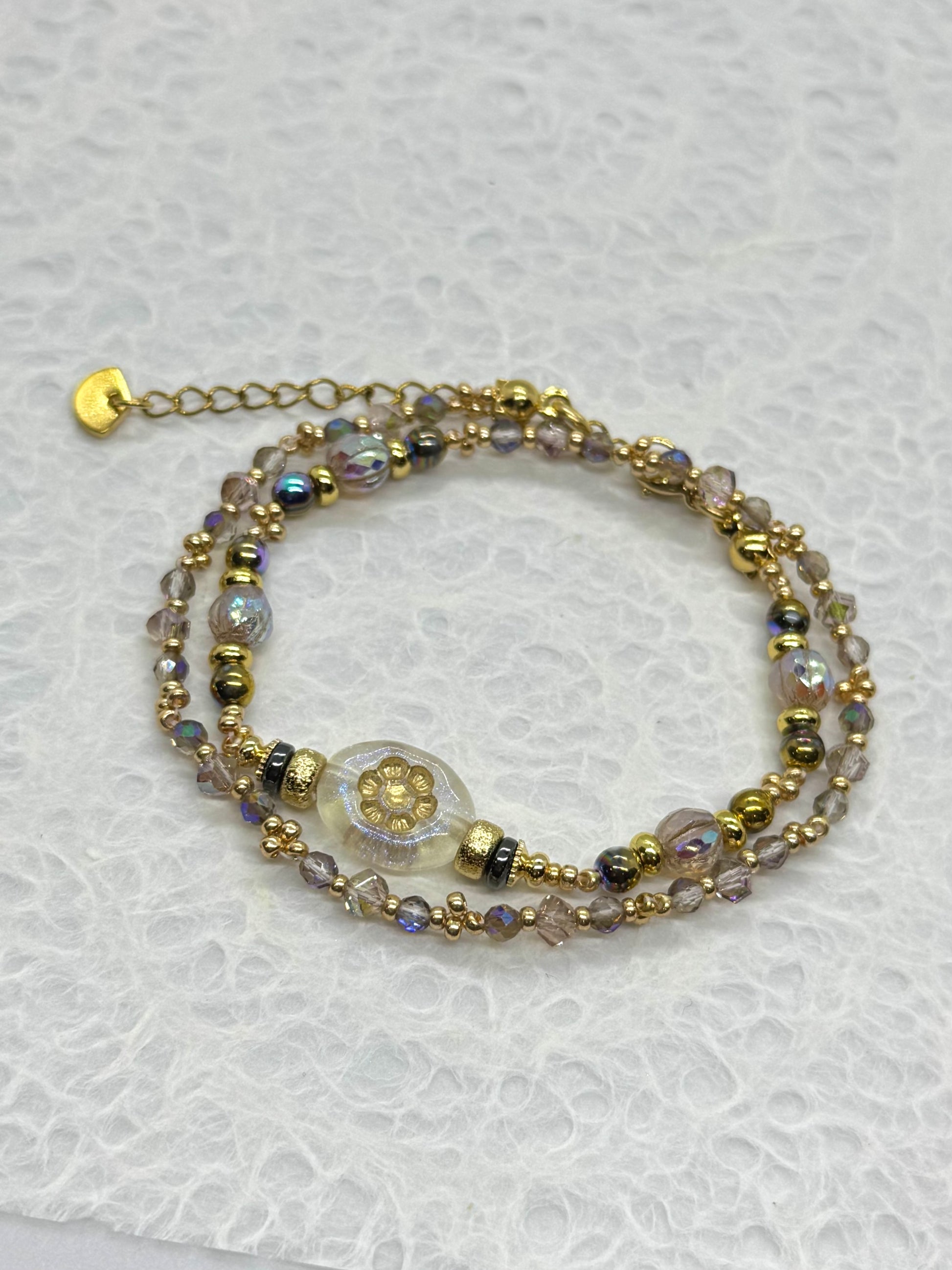 Multistrand beaded bracelet with gold accents on a textured white surface