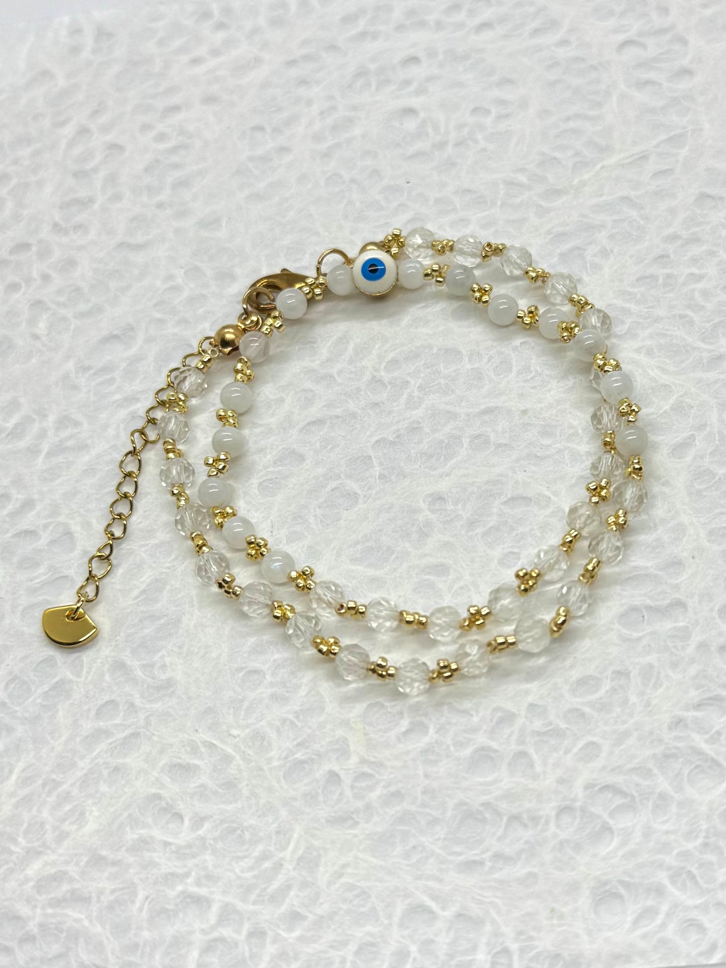 Two beaded bracelets with gold accents on a textured white background