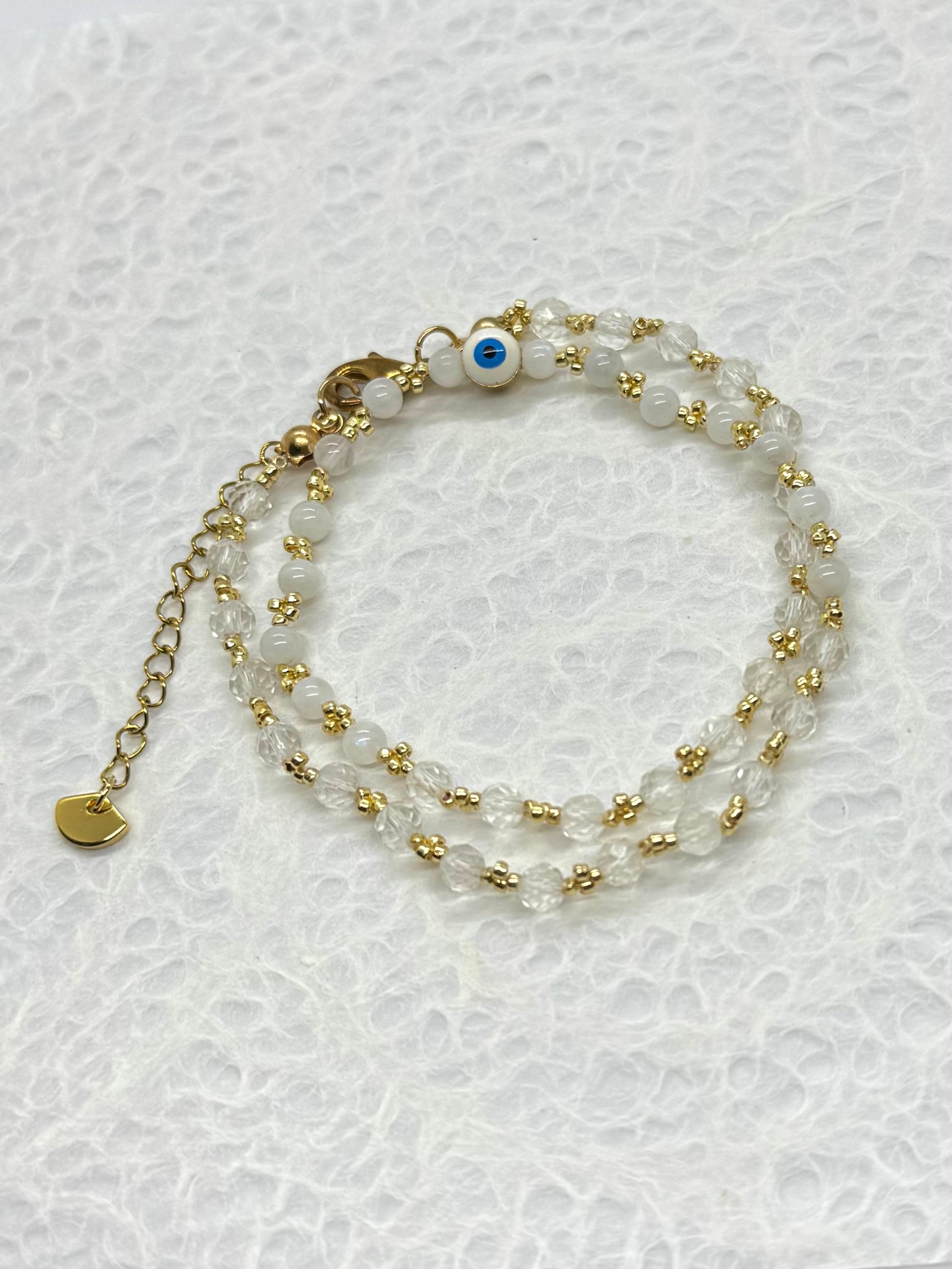 Two beaded bracelets with gold accents on a textured white background