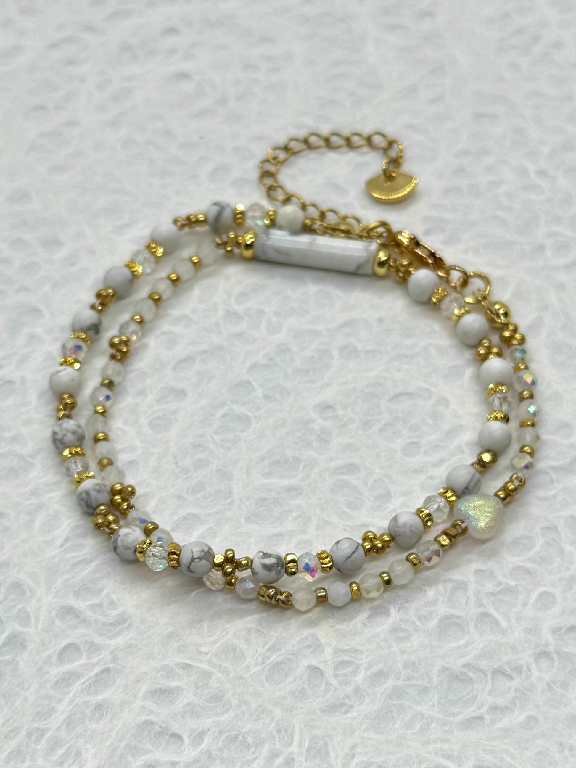 Beaded bracelet with gold and white beads on a textured white background