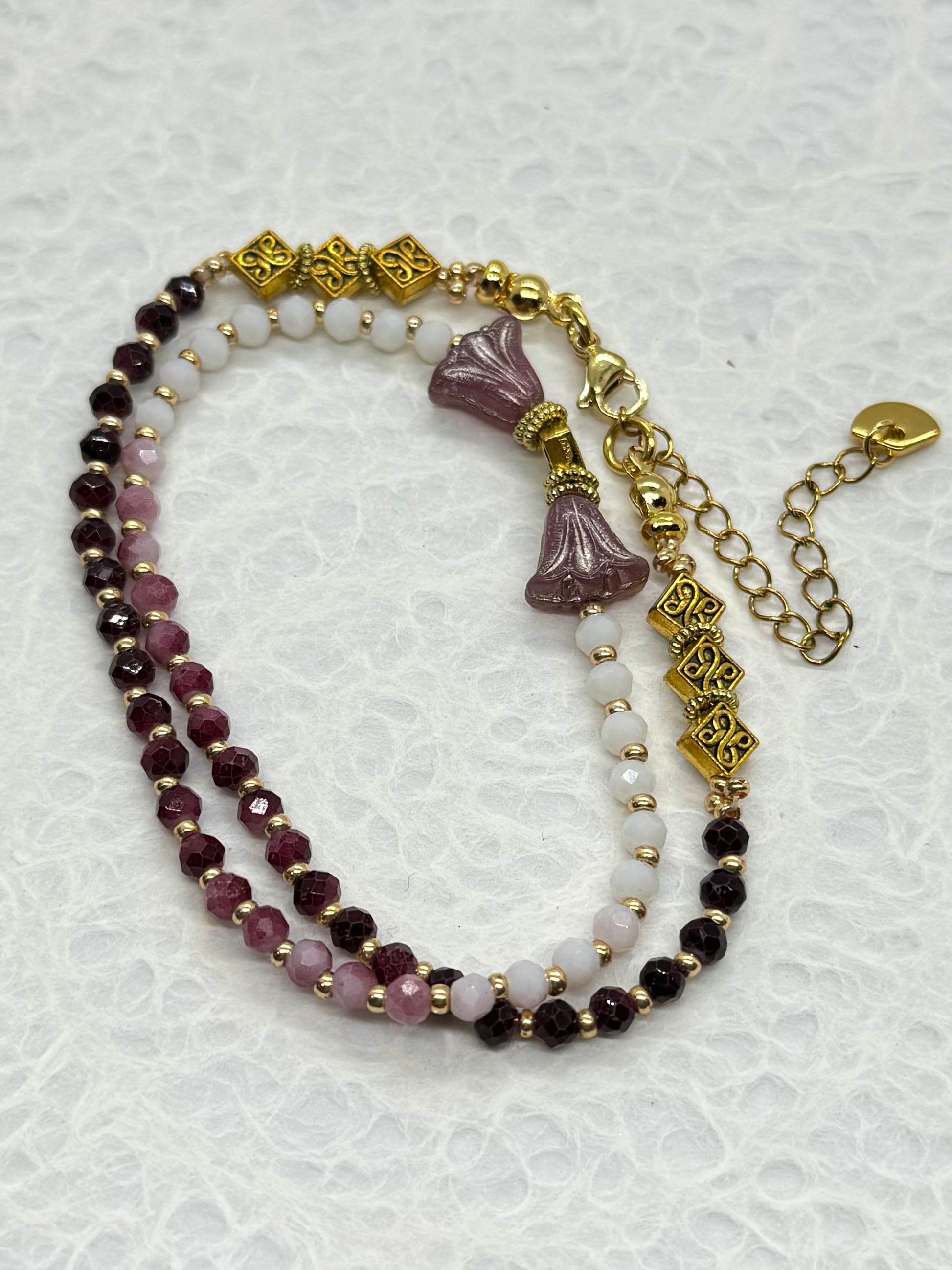 Multistrand beaded bracelet with gold accents on a textured white background