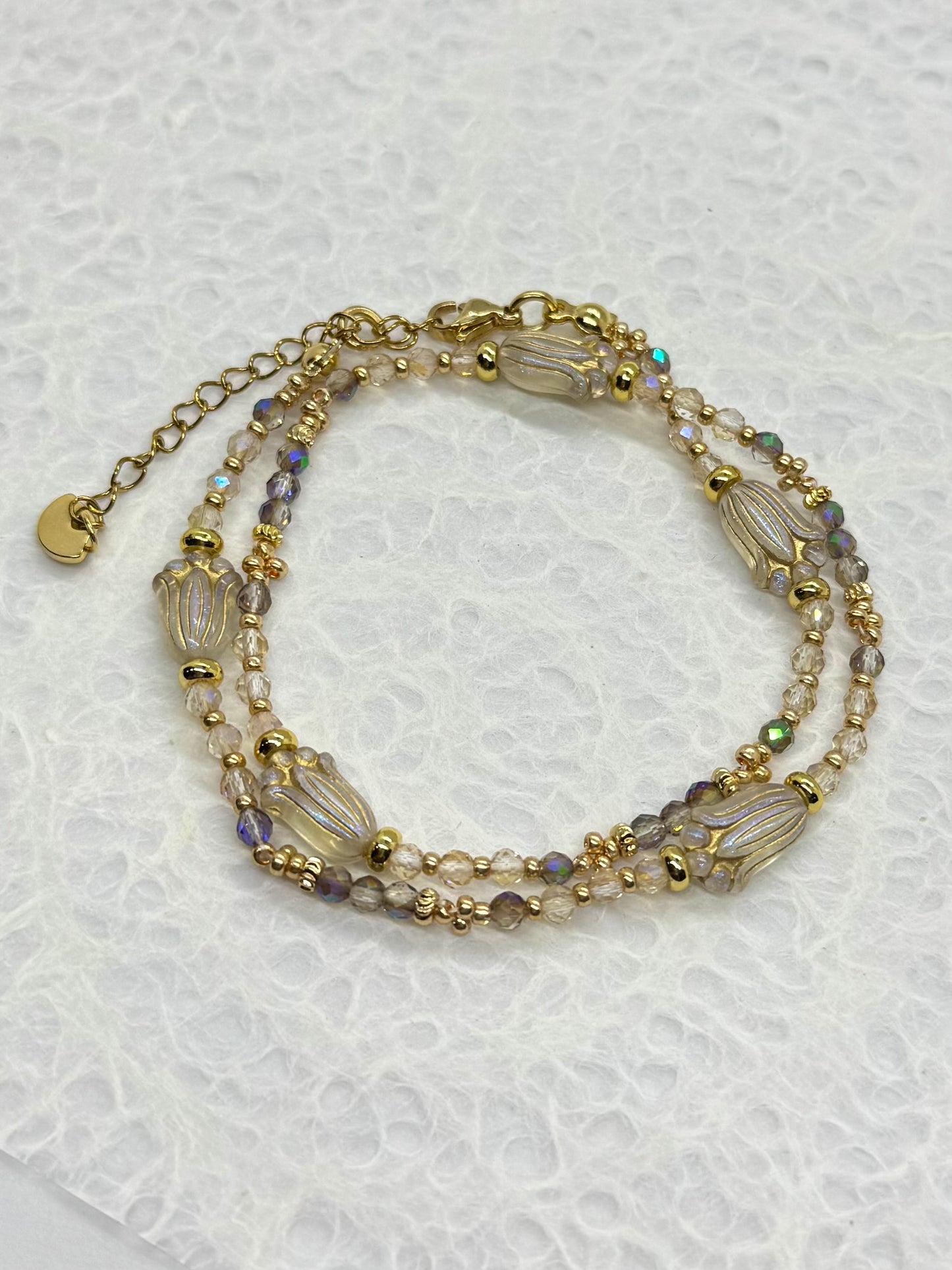 Multistrand beaded bracelet with gold accents on a textured white background