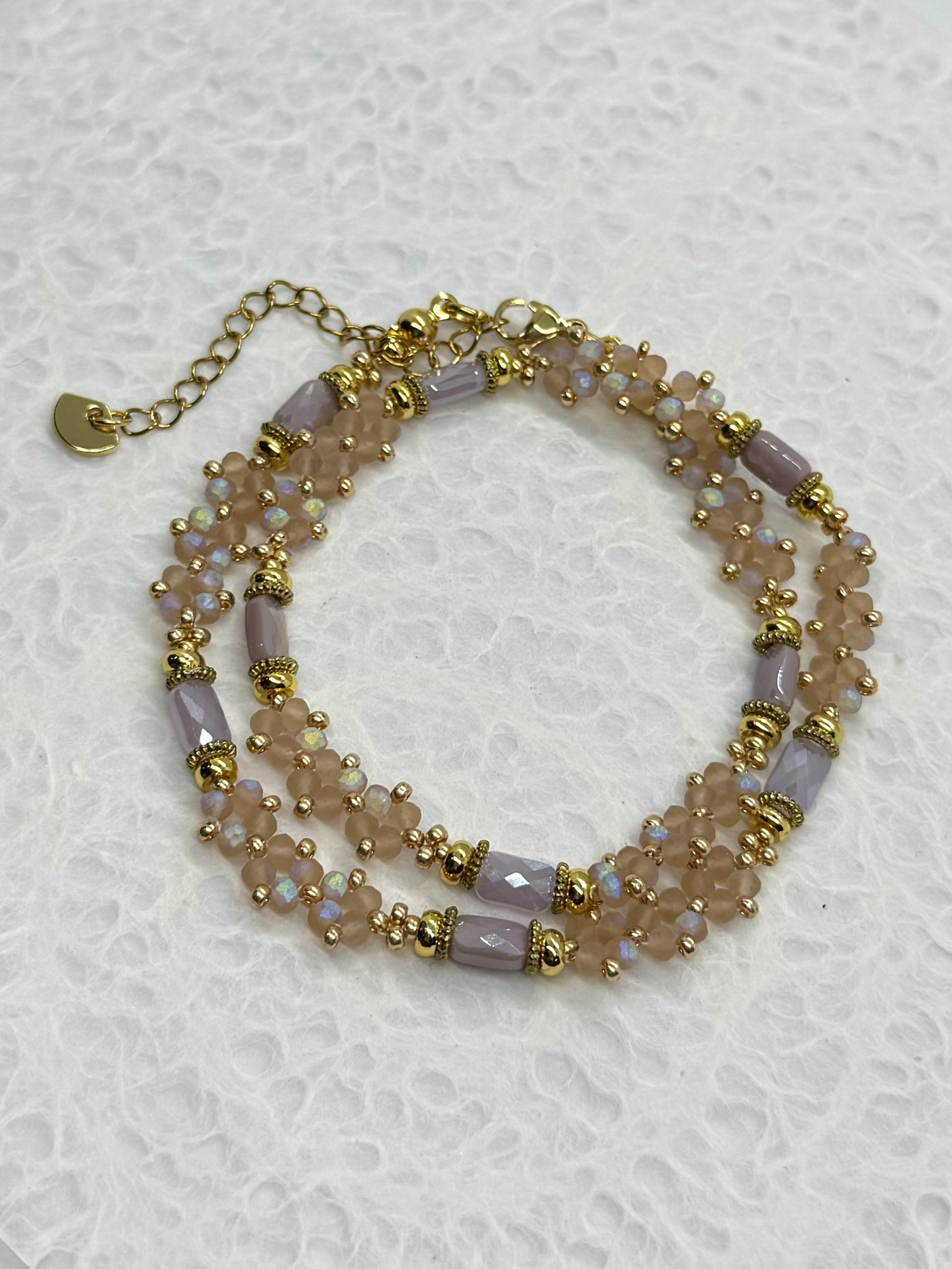 Multistrand beaded bracelet with gold accents on a textured white background