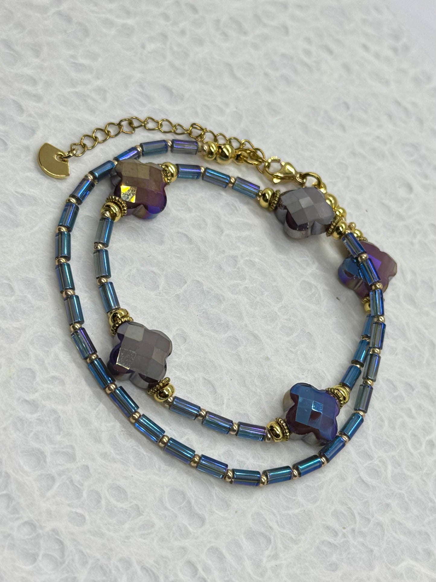 Multistrand bracelet with blue beads and gold accents on a textured white background