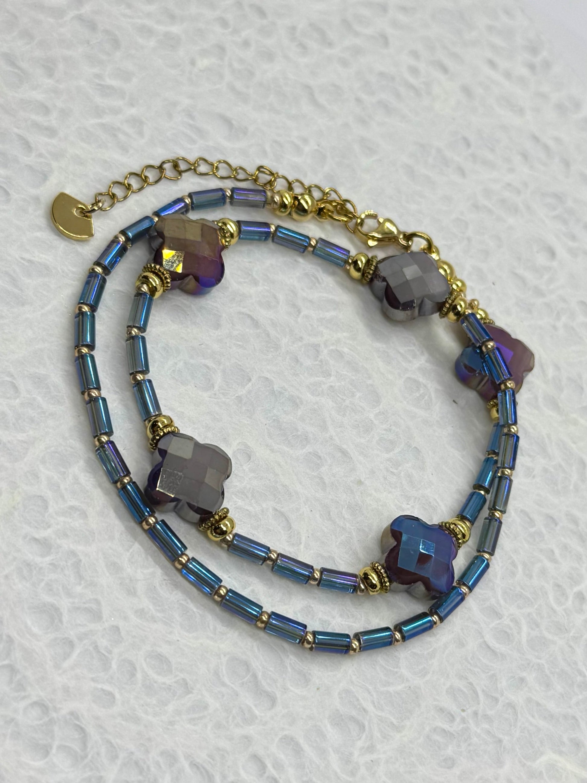 Multistrand bracelet with blue beads and gold accents on a textured white background