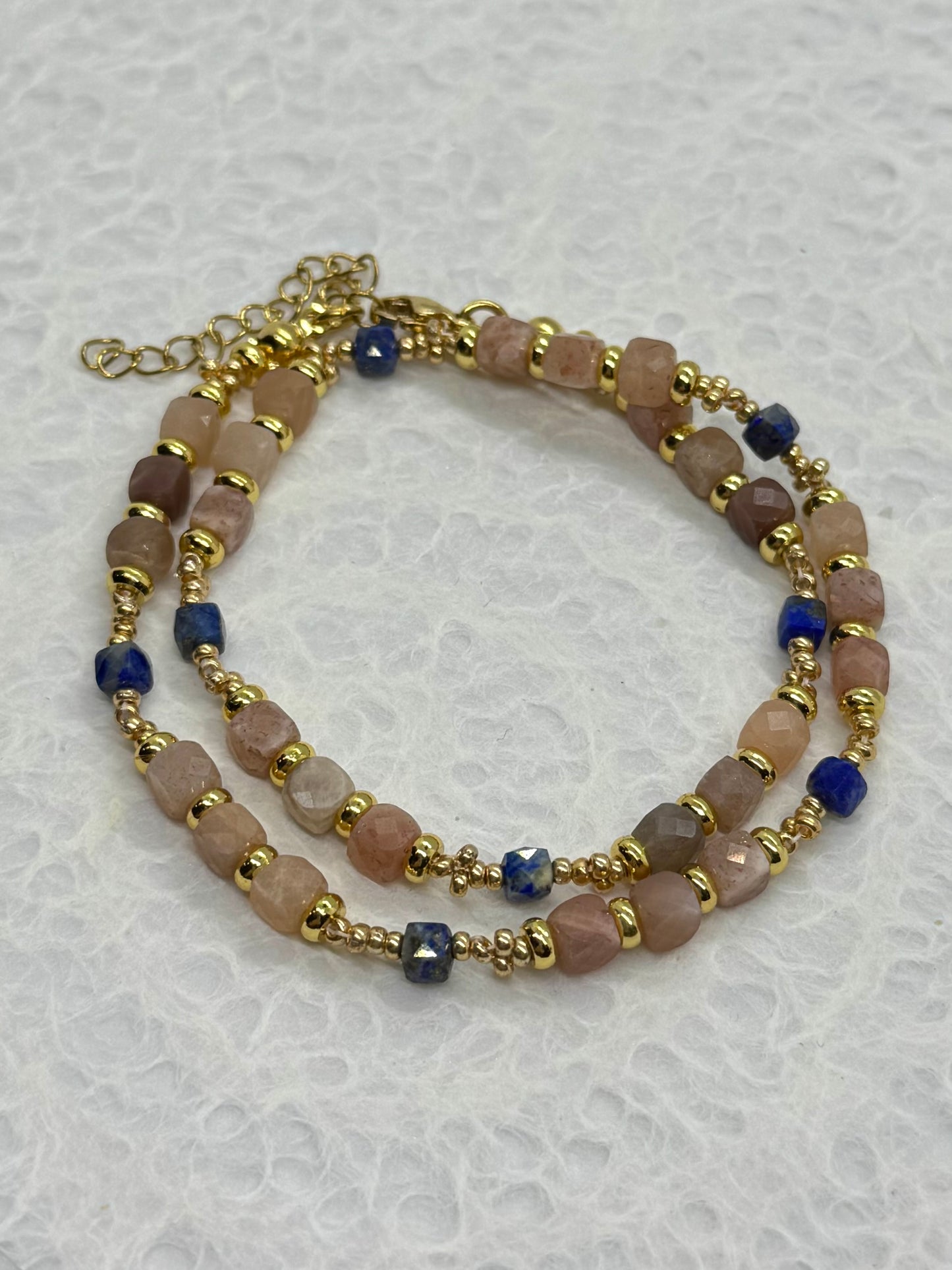 Beaded bracelet with gold accents on a textured white background