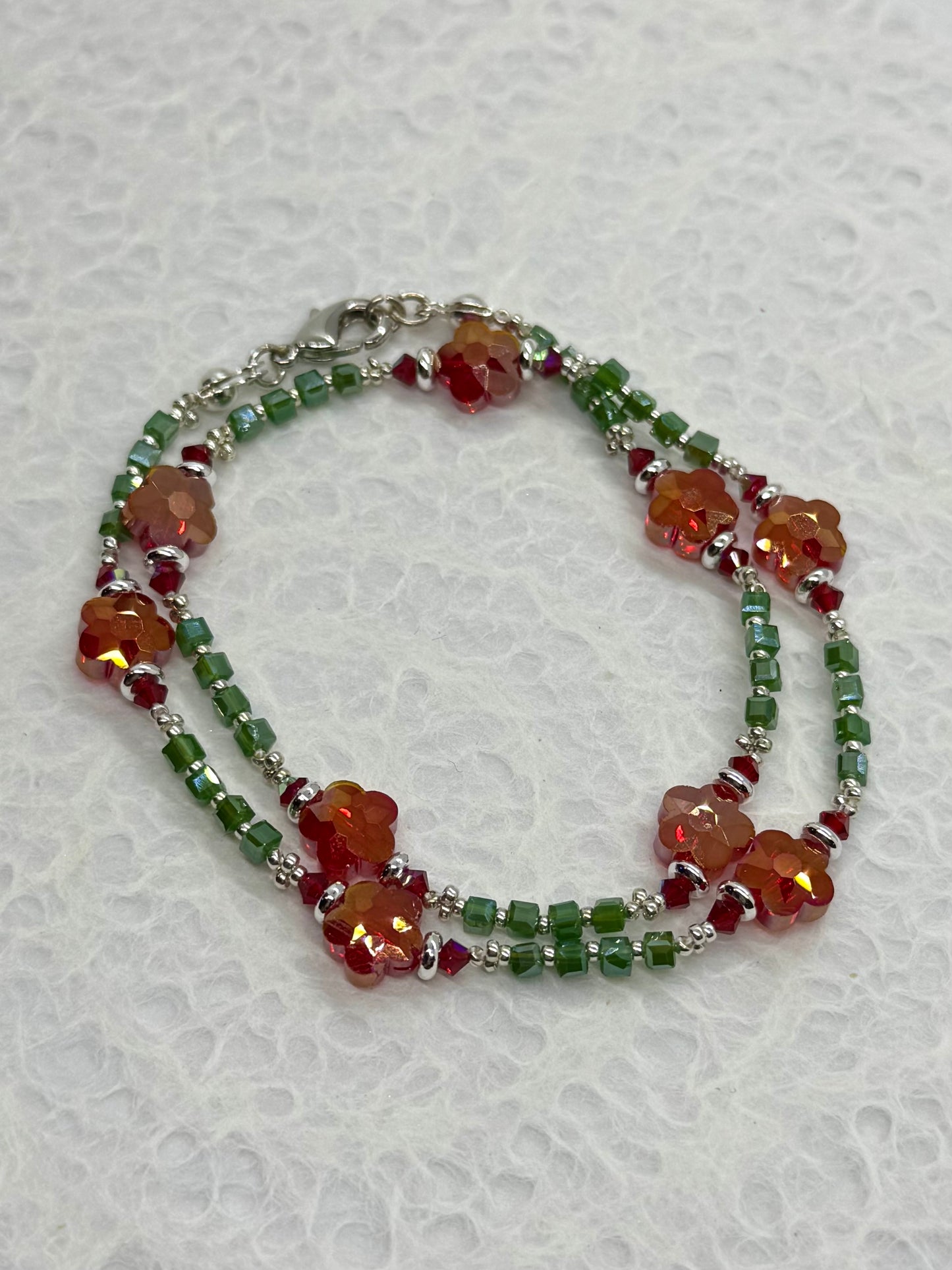 Beaded bracelet with orange and green beads on a textured white background