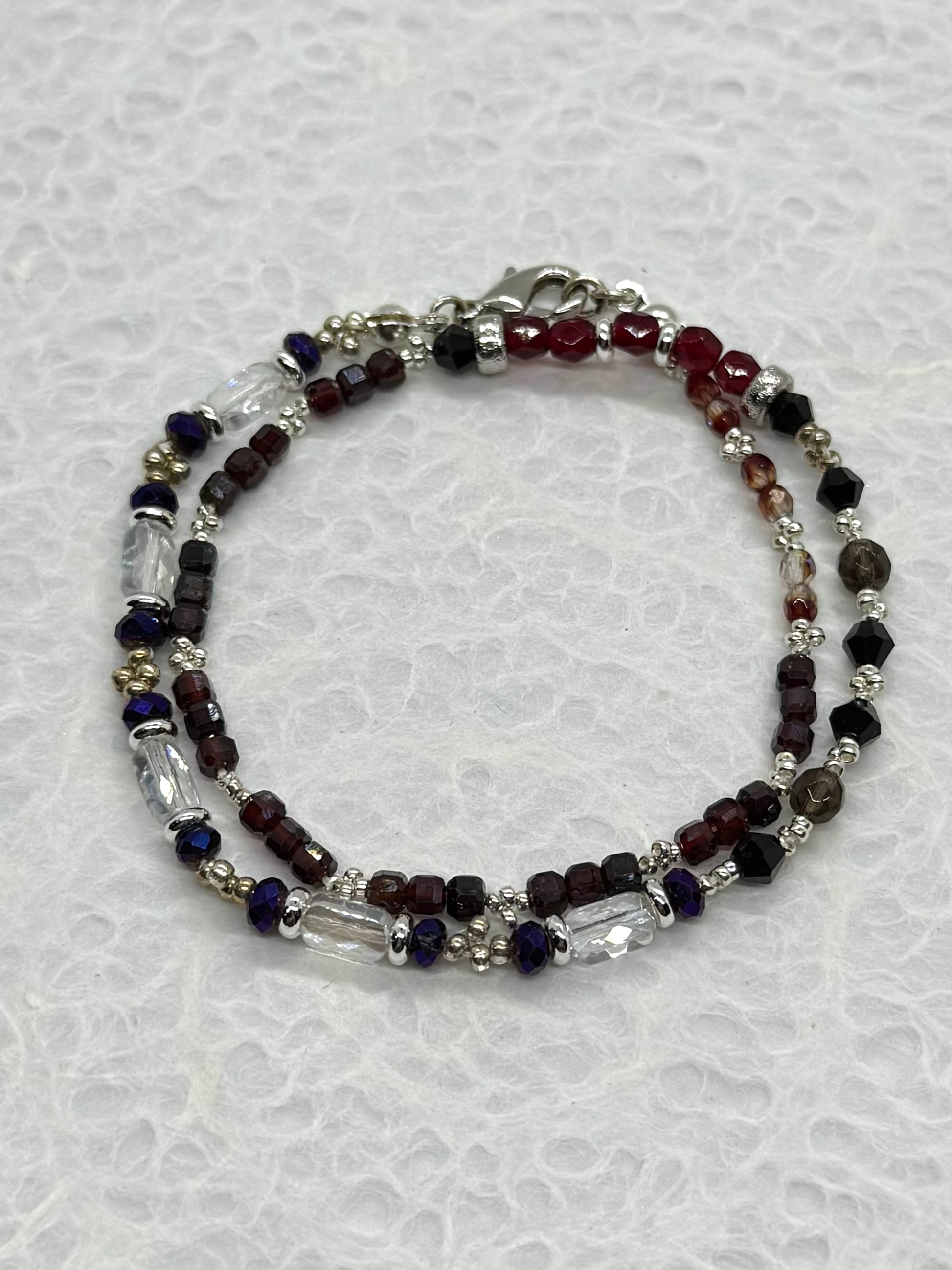 Beaded bracelet with red, blue, and clear beads on a white background