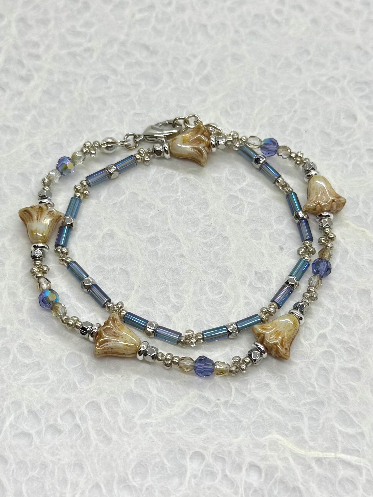 Bracelet with blue beads and shell-like elements on a textured white background