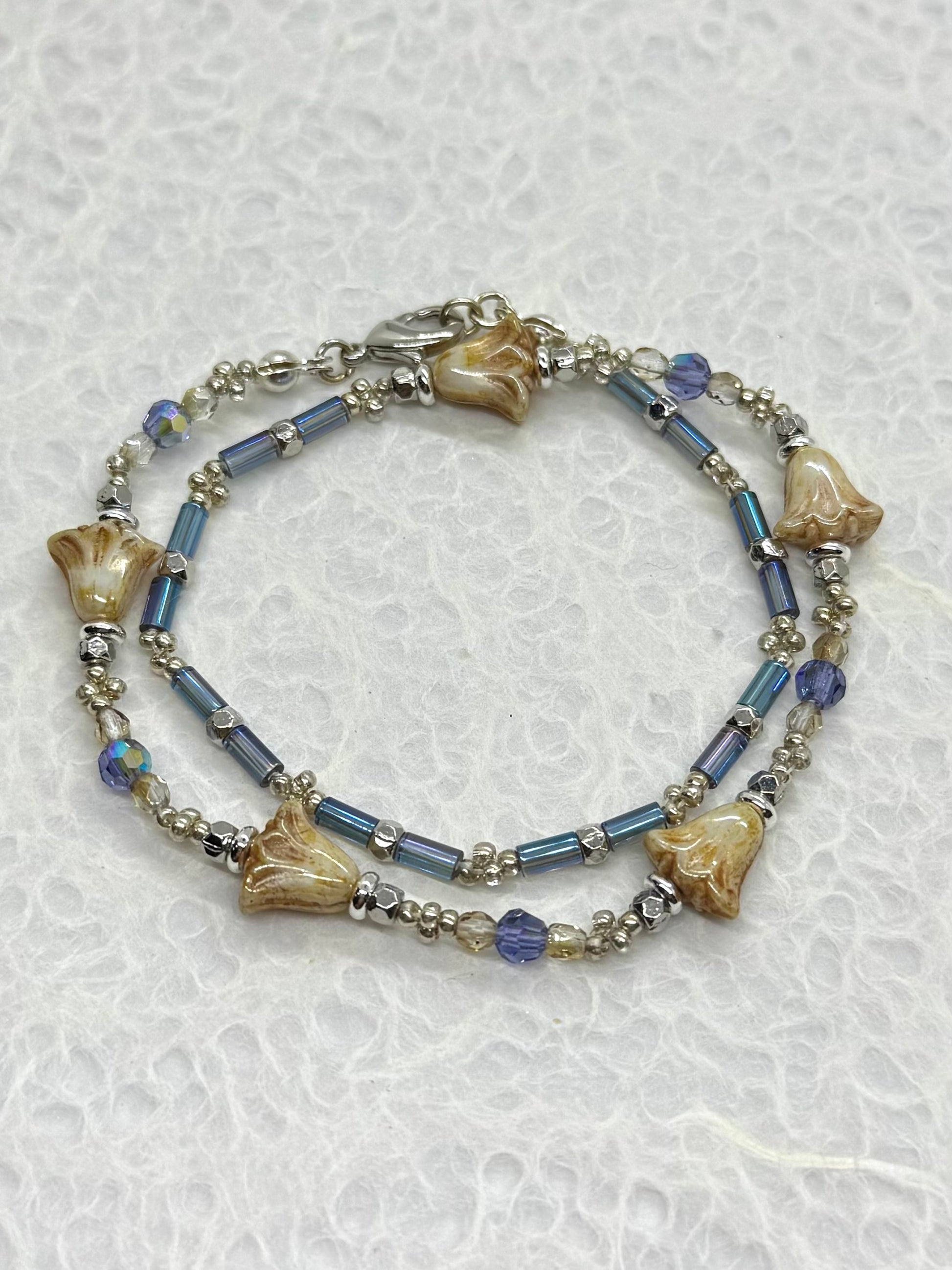 Bracelet with blue beads and shell-like elements on a textured white background