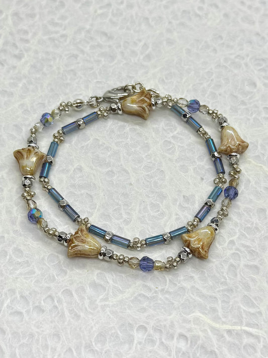 Bracelet with blue beads and shell-like elements on a textured white background