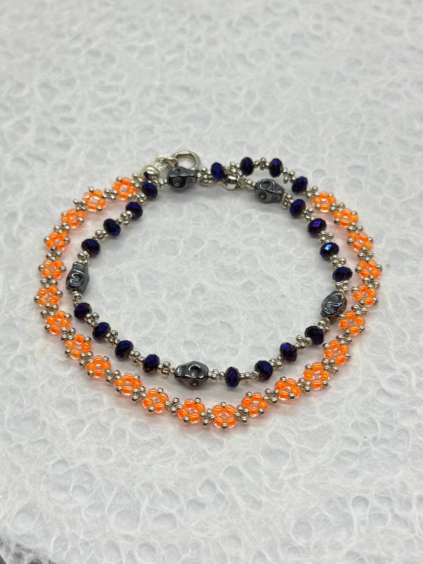Double-layered bracelet with orange and blue beads on a textured white background
