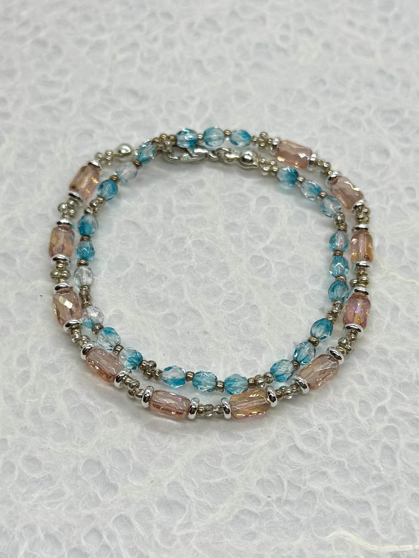 Beaded bracelet with blue and pink beads on a textured white background
