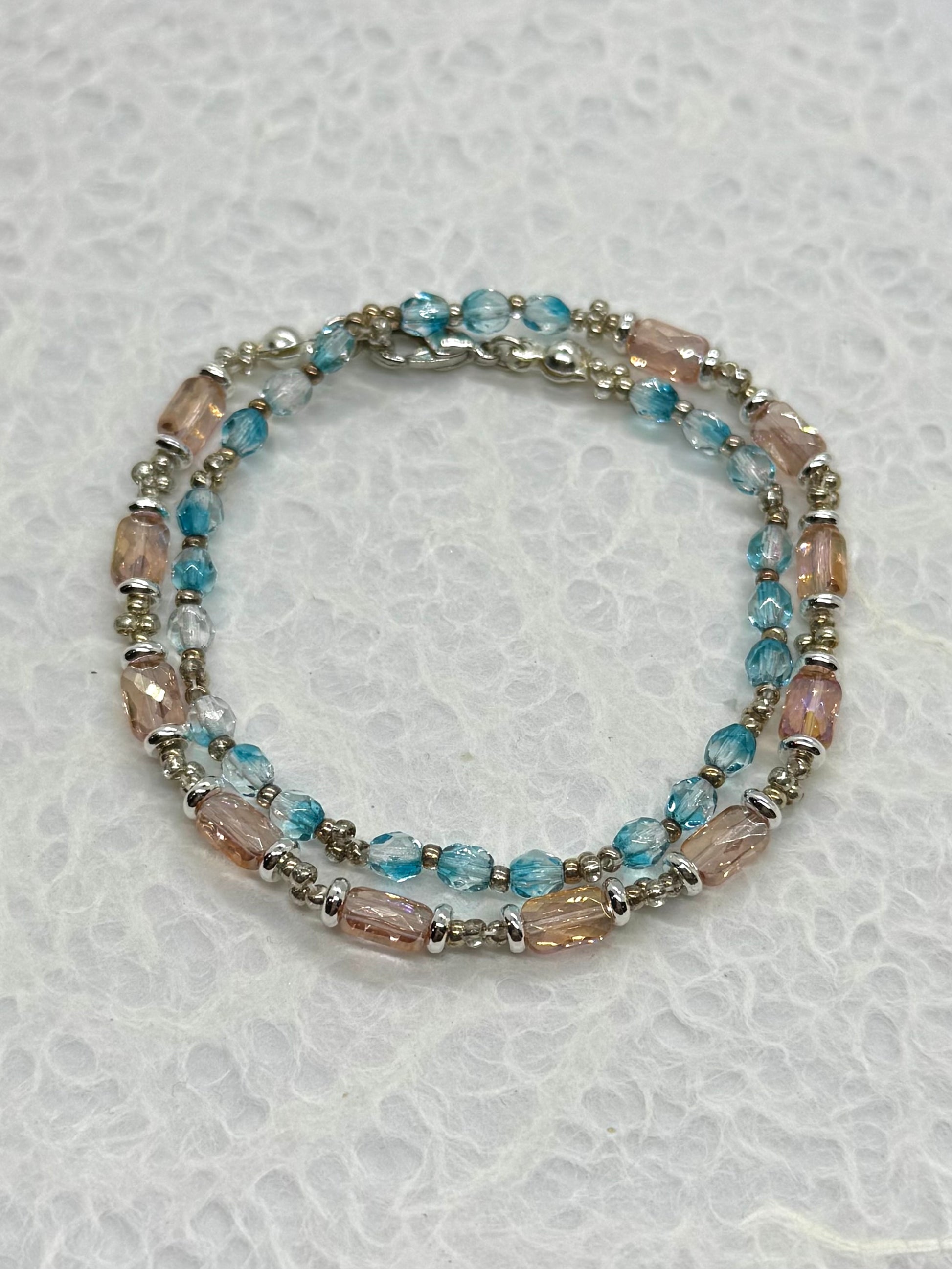 Beaded bracelet with blue and pink beads on a textured white background