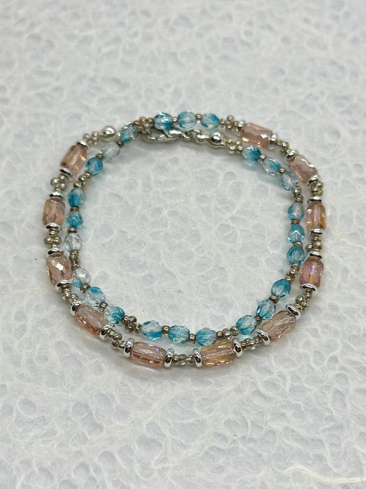 Beaded bracelet with blue and pink beads on a textured white background