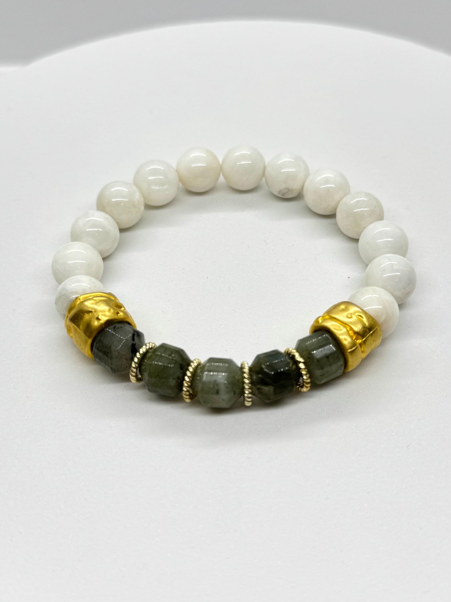 Beaded bracelet with white, black, and gold beads on a white background