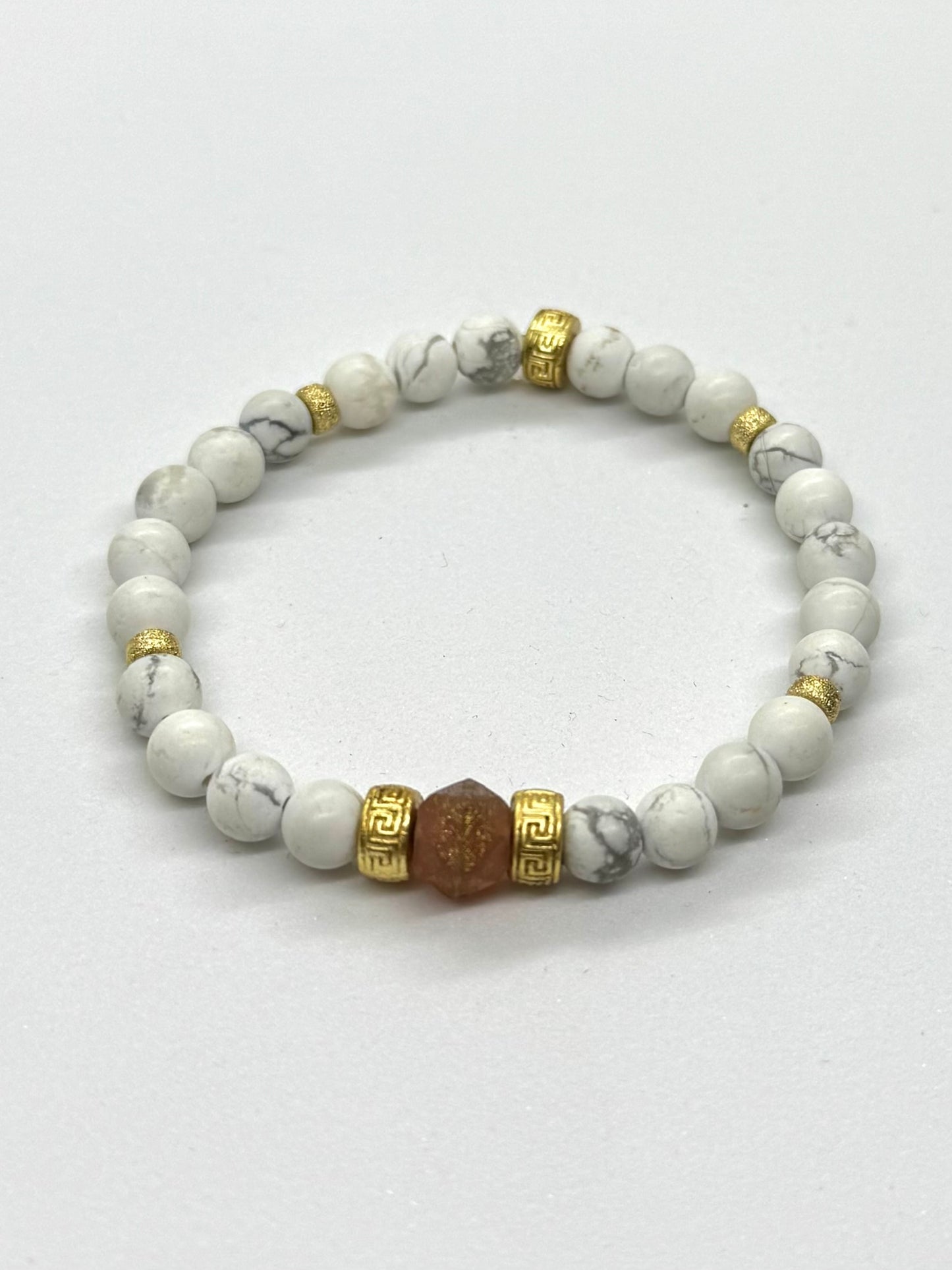 Beaded bracelet with white stones and gold accents on a light gray background