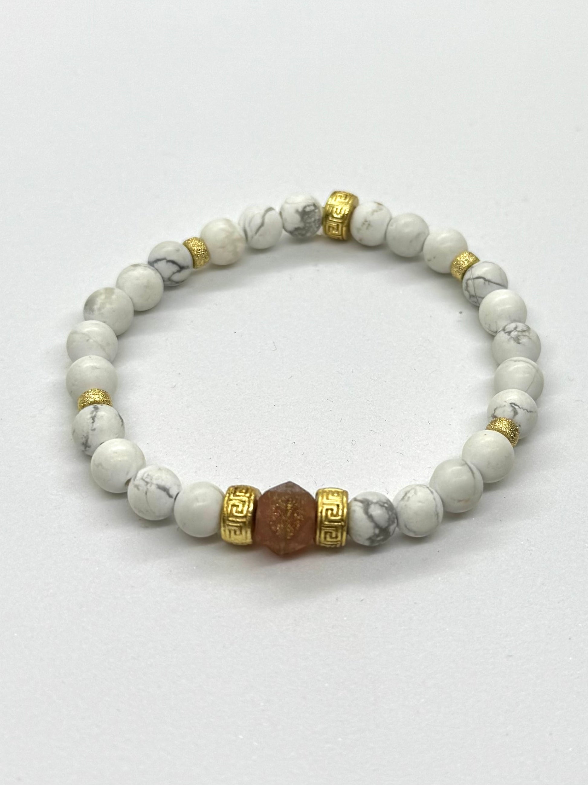 Beaded bracelet with white stones and gold accents on a light gray background
