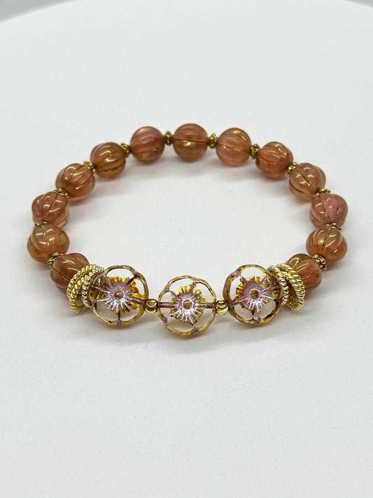 Bracelet with brown beads and gold accents on a white background