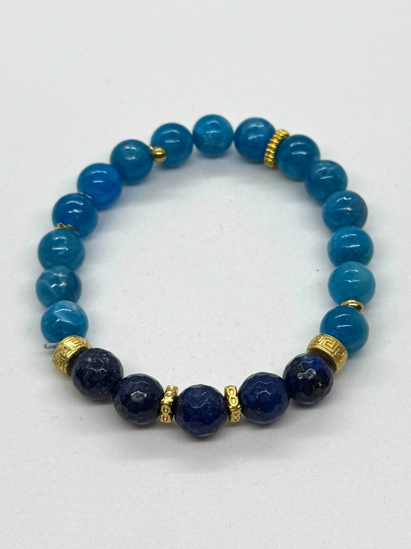 Blue beaded bracelet with gold accents on a white background
