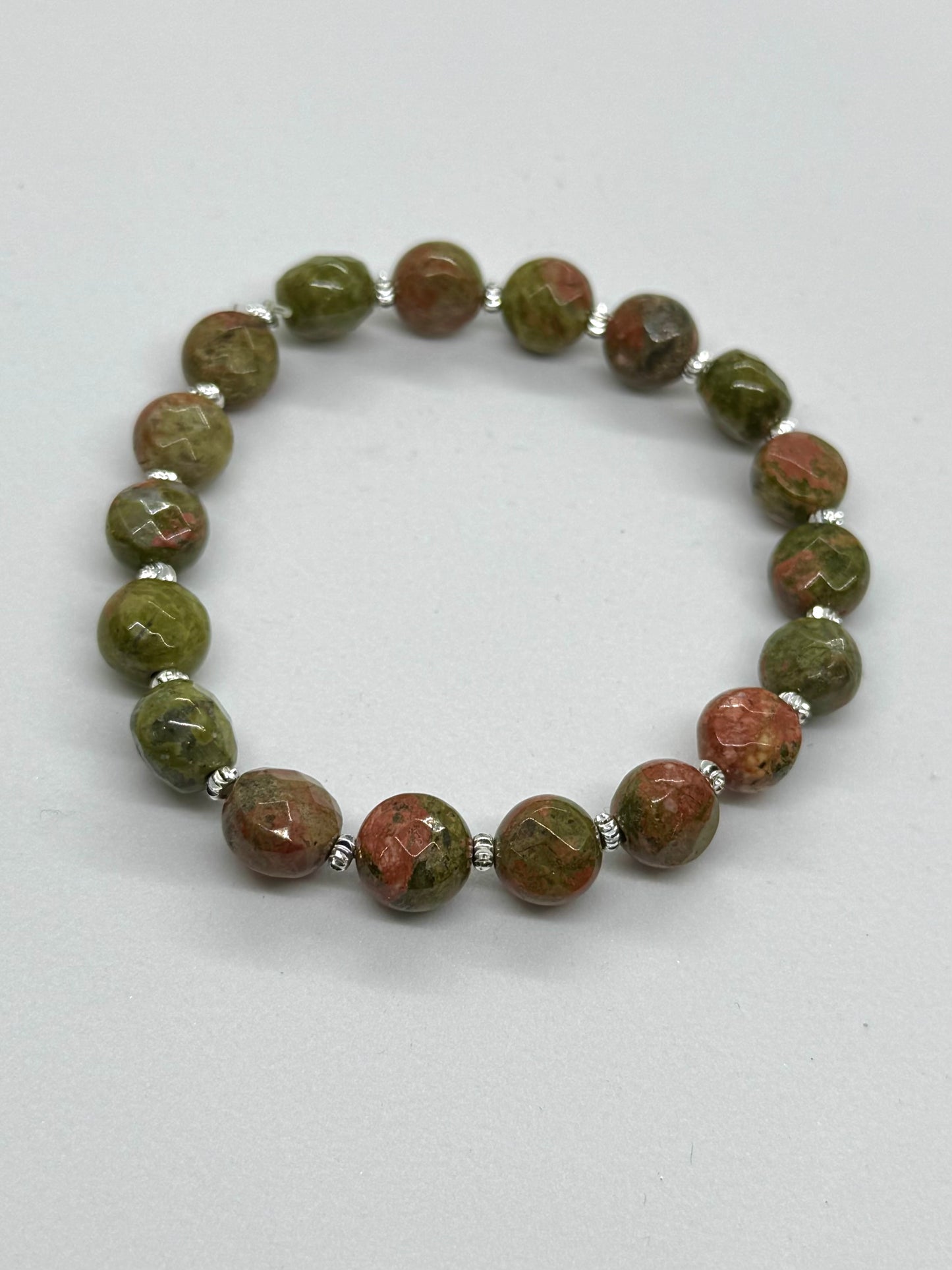 Beaded bracelet with green and brown stones on a white background